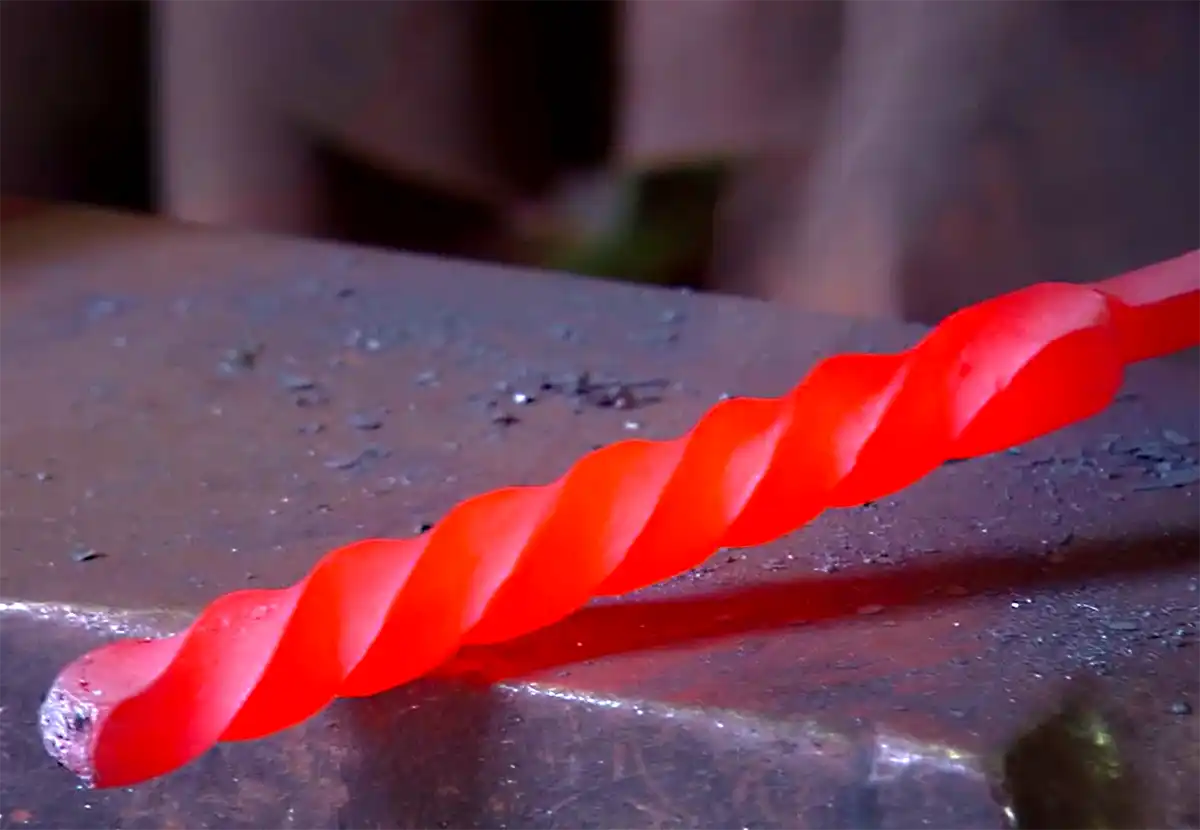 Laguiole-Messer-Damaststahl-drehen Rot glühender gedrehter Damaststahl in einer Schmiede für ein Laguiole Messer