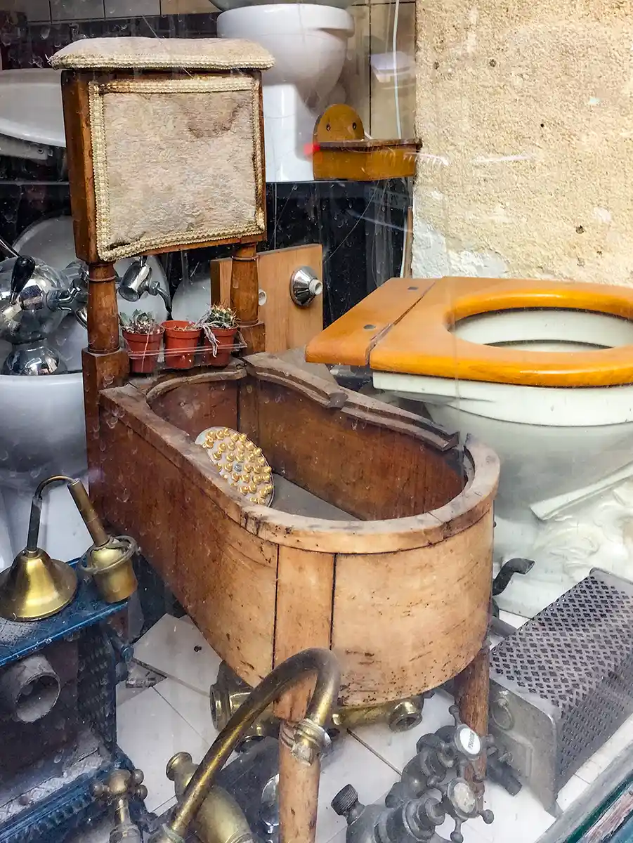 Schaufenster mit verstaubtem alten Holzbidet und einer alten Toilette