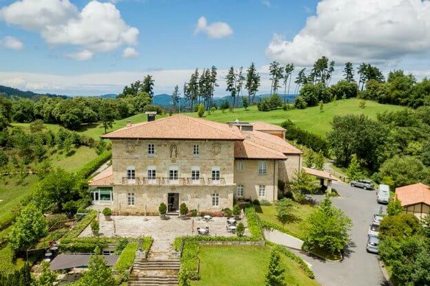 Der wiederaufgebaute Palacio Urgoiti von außen im Sonnenschein mit Blick über die Hügel