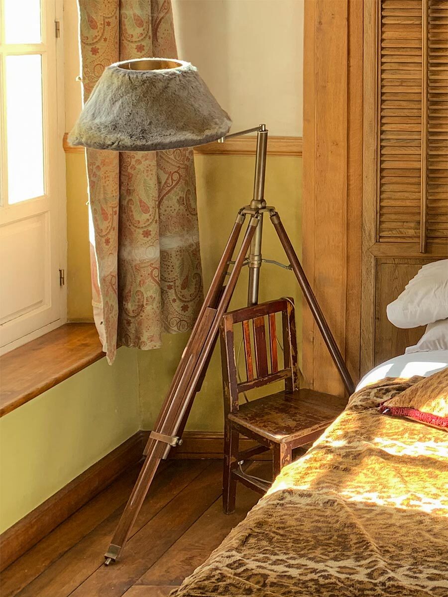 Kolonialstil-Lampe-Fellbezug Mit Fell bezogener Lampenschirm neben einem Bett am Fenster mit Sonnenlicht
