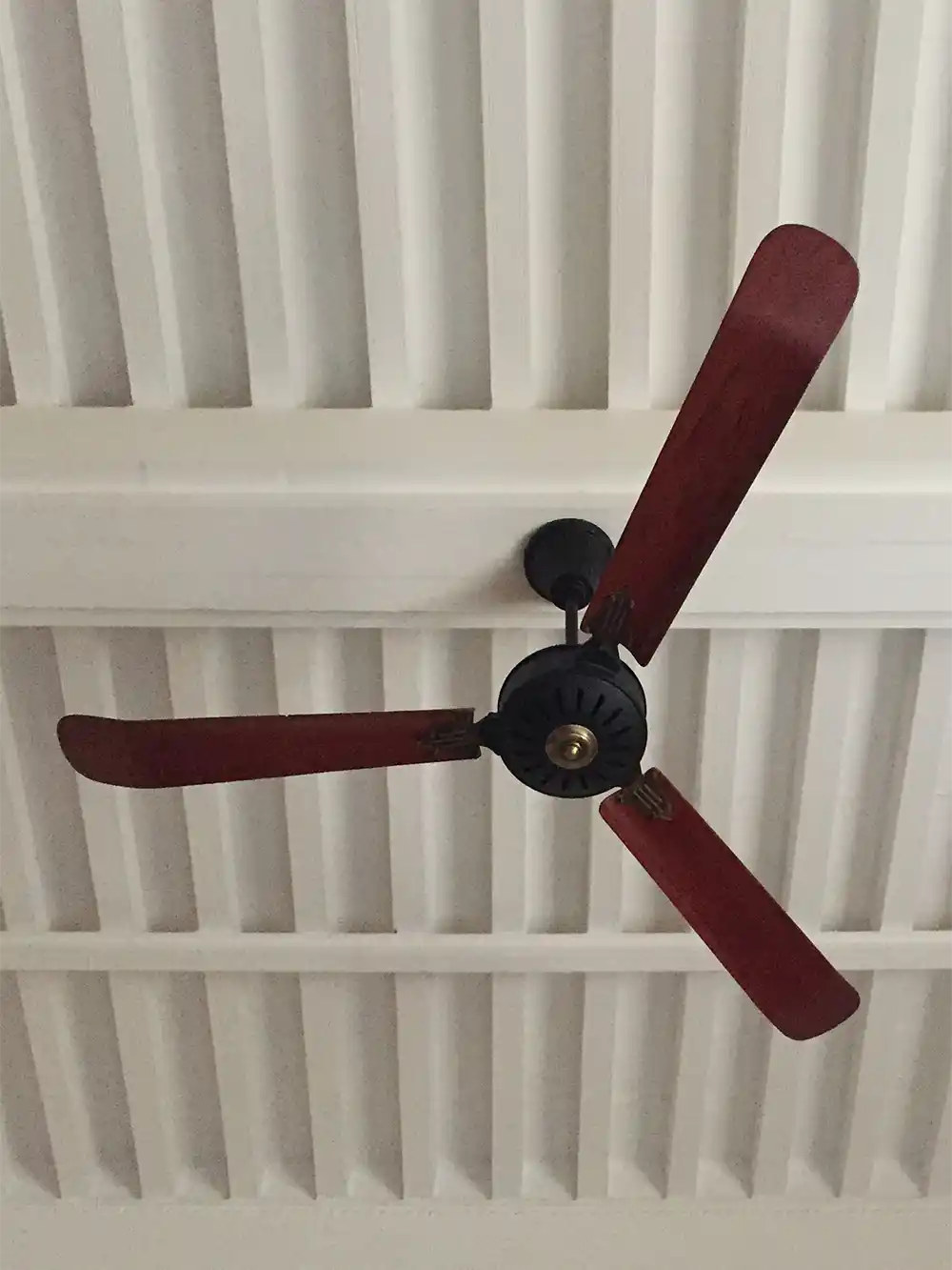 Kolonialstil-Ventilator2 Ventilator aus rotem Holz vor weißer Holzdecke