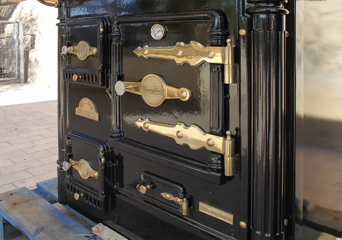 Nahaufnahme eines alten Range Cookers in Schwarz und Messing mit verzierten Griffen und mehreren Fächern.