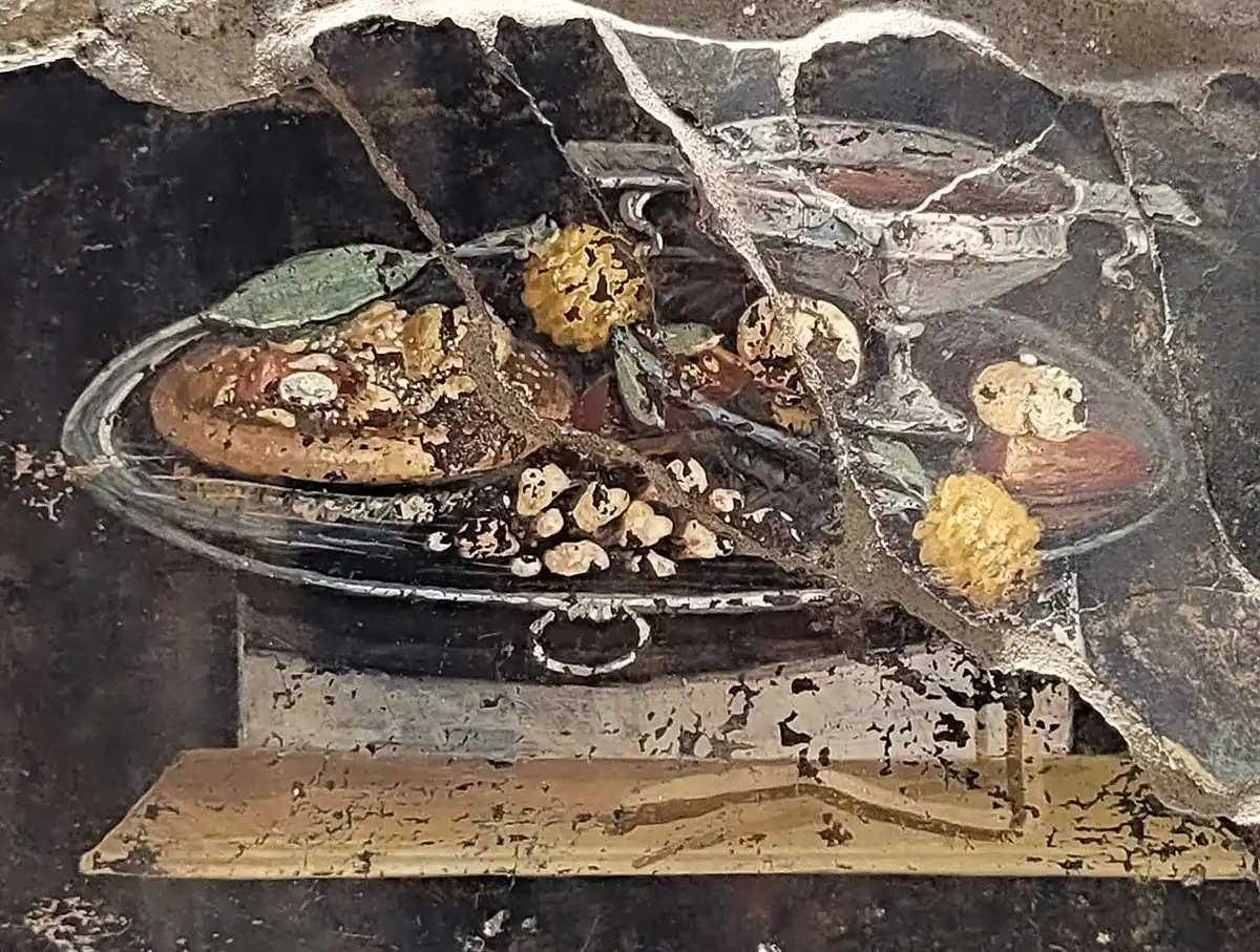 Pizza-Pompeji Antikes Fresko eines Speisetellers mit Brot, Obst und einem silbernen Becher, teilweise beschädigt und zerbrochen.