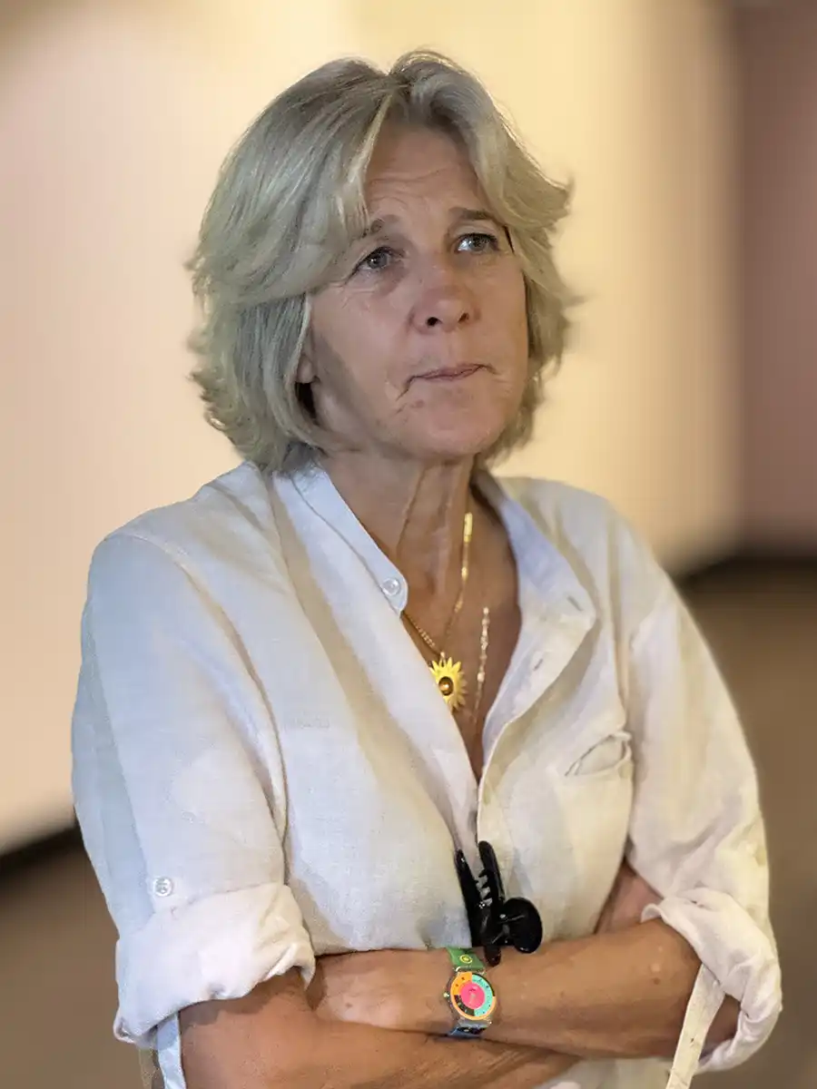 Florett-Hayot-HSE Ältere Frau mit kurzen blonden Haaren und nachdenklichem Gesichtsausdruck, verschränkte Arme, weißes Hemd.