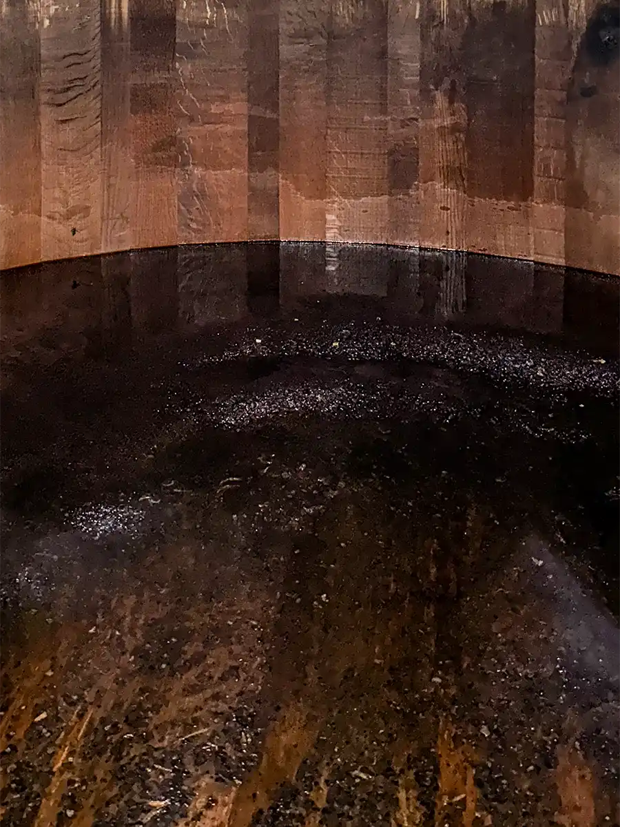 Rum-Fass-innen Dunkle Flüssigkeit füllt ein Holzfass, das die strukturierte Holzmaserung und die gewölbten Seiten des Behälters zeigt.