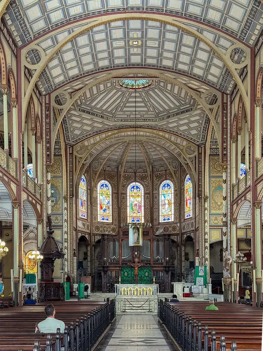 Sehenswurdigkeiten-Martinique-Kathedrale-innen Verziertes Kircheninnere mit gewölbter Decke, bunten Glasfenstern und leeren Holzbänken vor dem Altar.