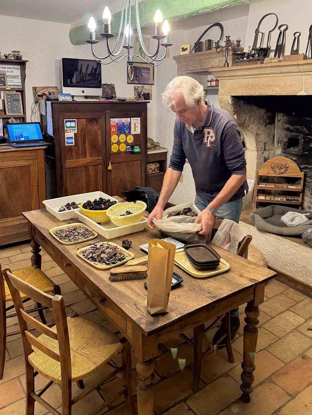 Ayme-Verkaufsraum Ein Mann mit weißen Haaren beugt sich in einem kleinen Raum über eine Tüte mit Trüffeln