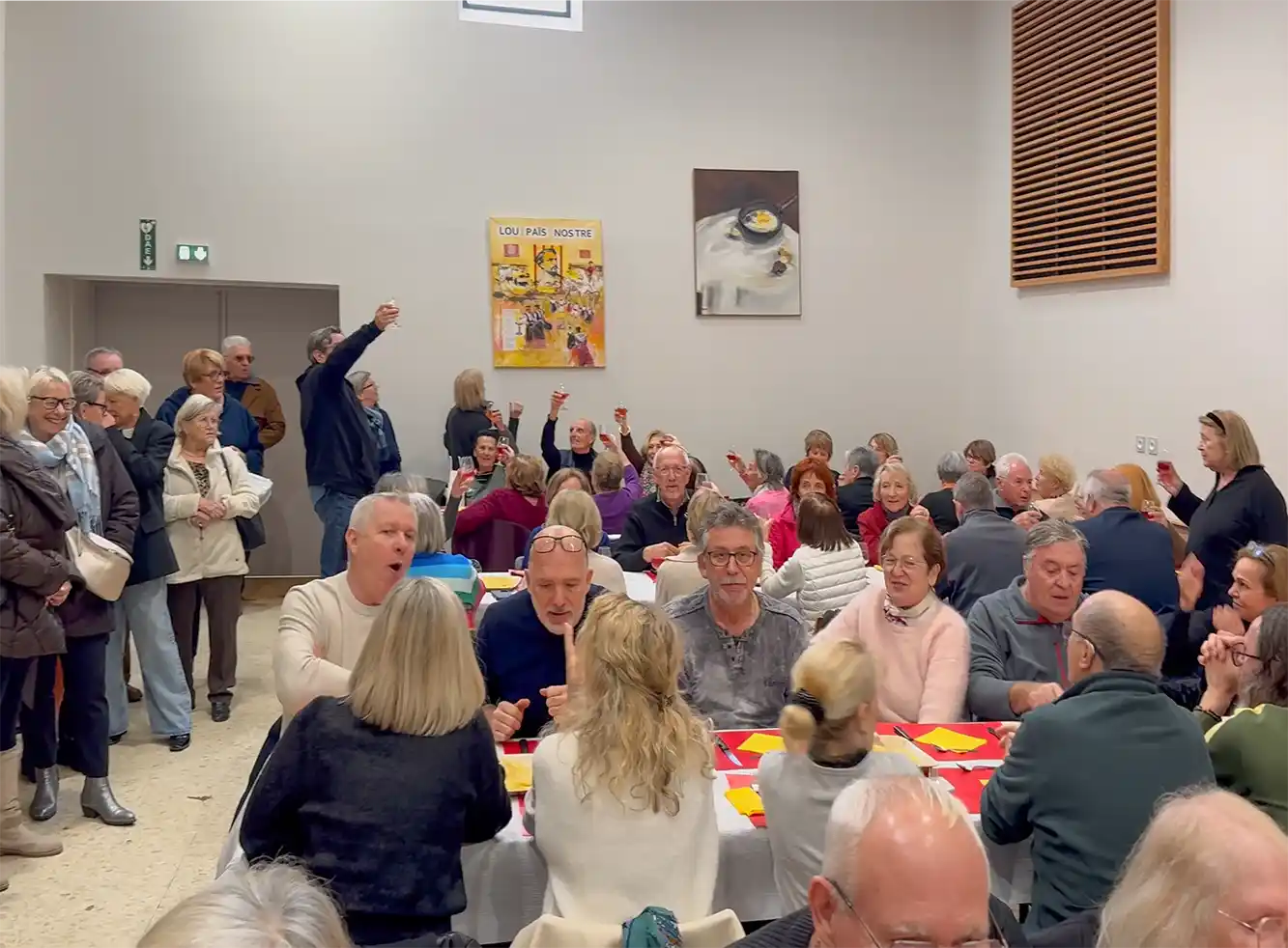 Trueffel-Omelette-verkostung In einem Saal mit vielen Menschen an Tischen heben einige das Glas ihoch und prosten sich zu