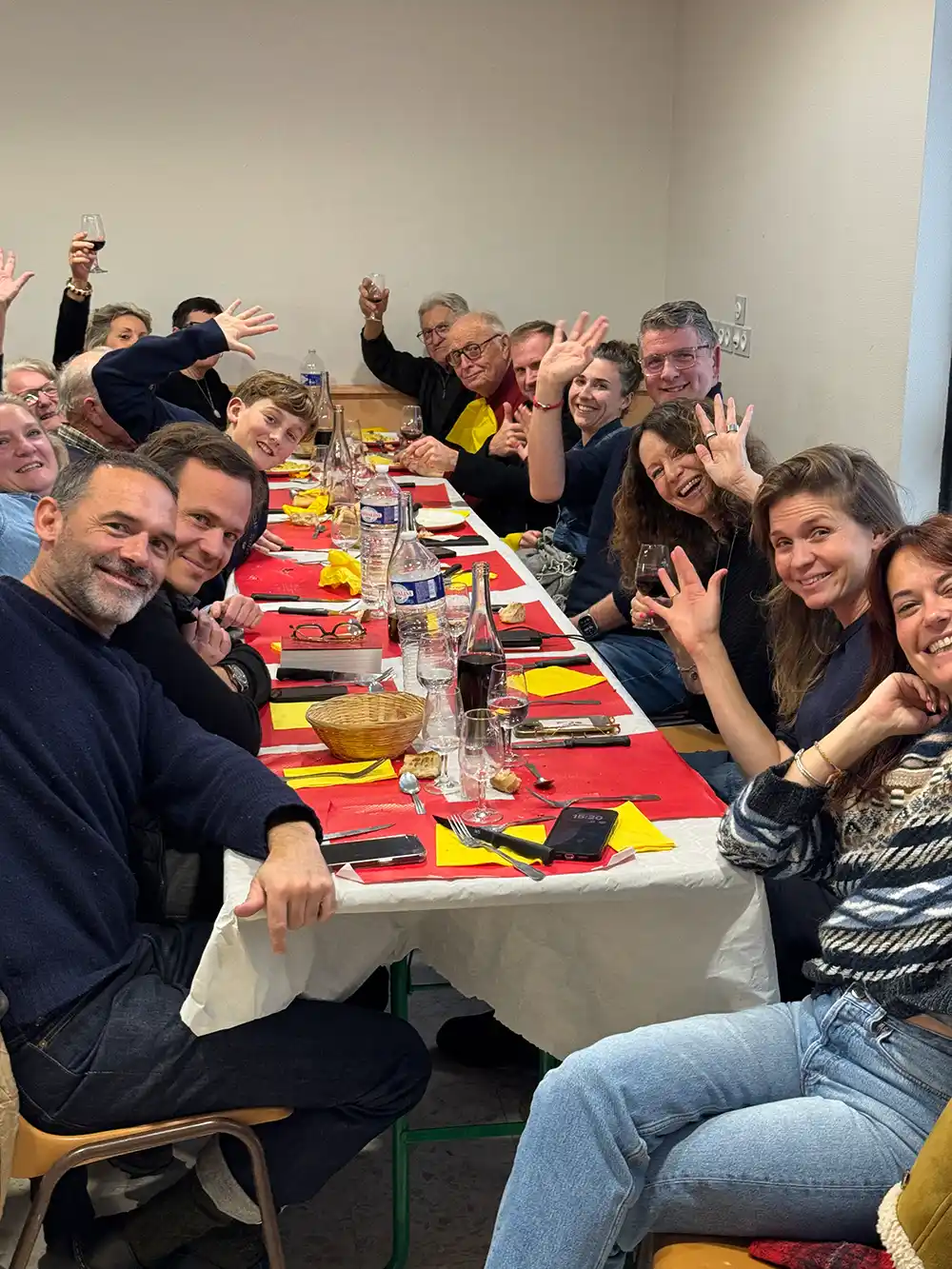 Trueffelmarkt-Richerenches-Trueffelomelette-Geselligkeit Menschen an einem langen Tisch lachen und winken in die Kamera