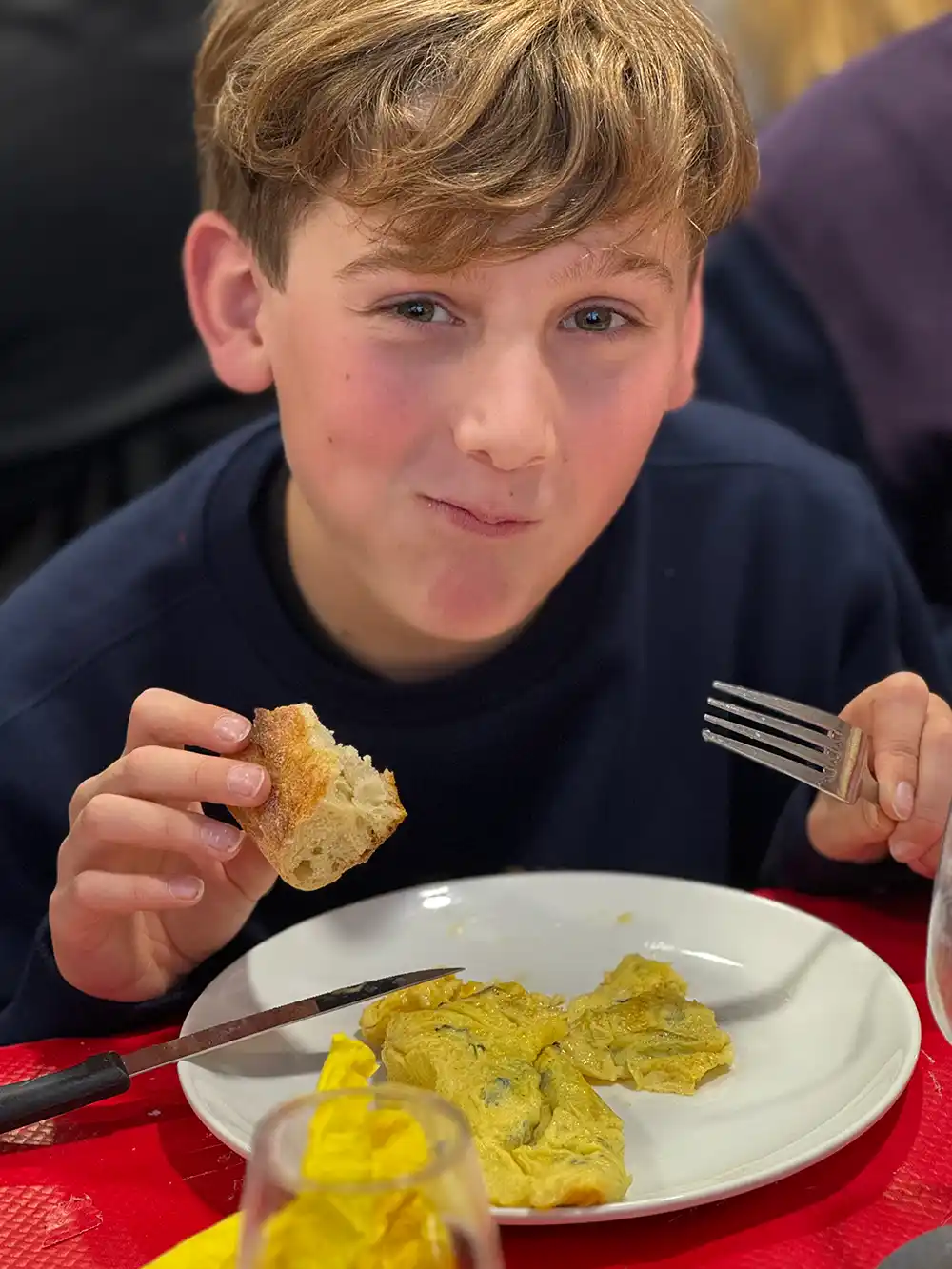Trueffelmarkt-Richerenches-Trueffelomelette-Junge Junge lächelt in die Kamera, während er ein Trüffelomelette isst