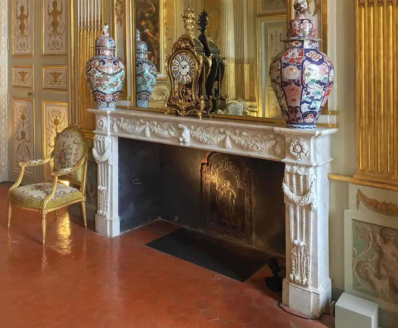 Verzierter Marmorkamin mit Vasen, antiker Uhr, vergoldetem Spiegel und elegantem Stuhl in einem großzügigen Raum.