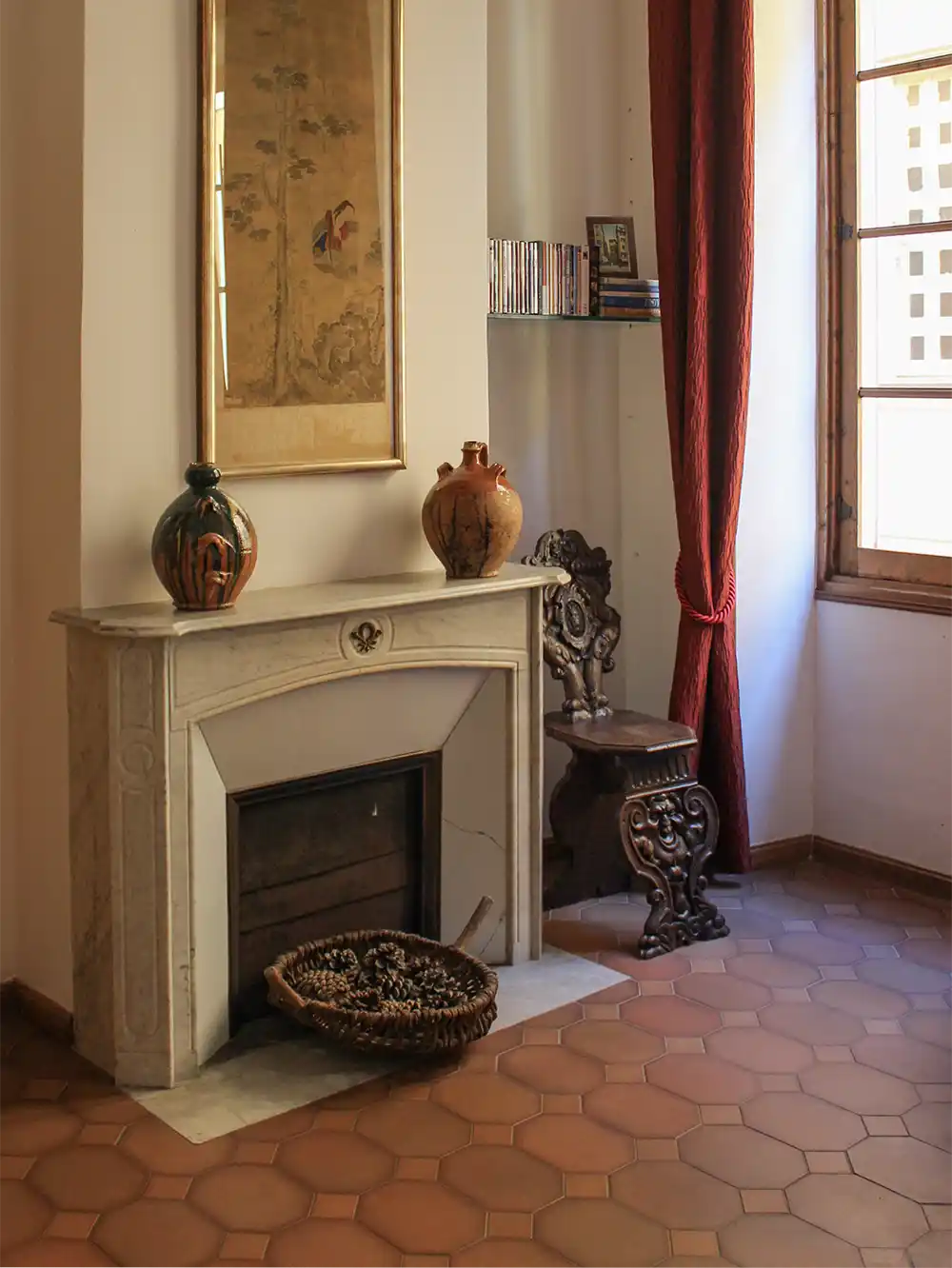 Eine gemütliche Ecke mit einem Marmorkamin, verzierten Stühlen, Vasen und Sonnenlicht, das durch ein Fenster fällt.