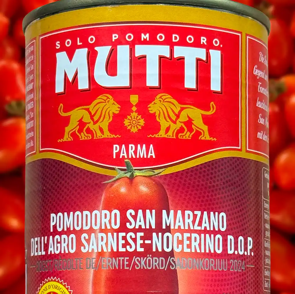Eine Mutti-Dose mit San Marzano-Tomaten mit rotem Etikett und goldenen Löwen, umgeben von frischen Tomaten.