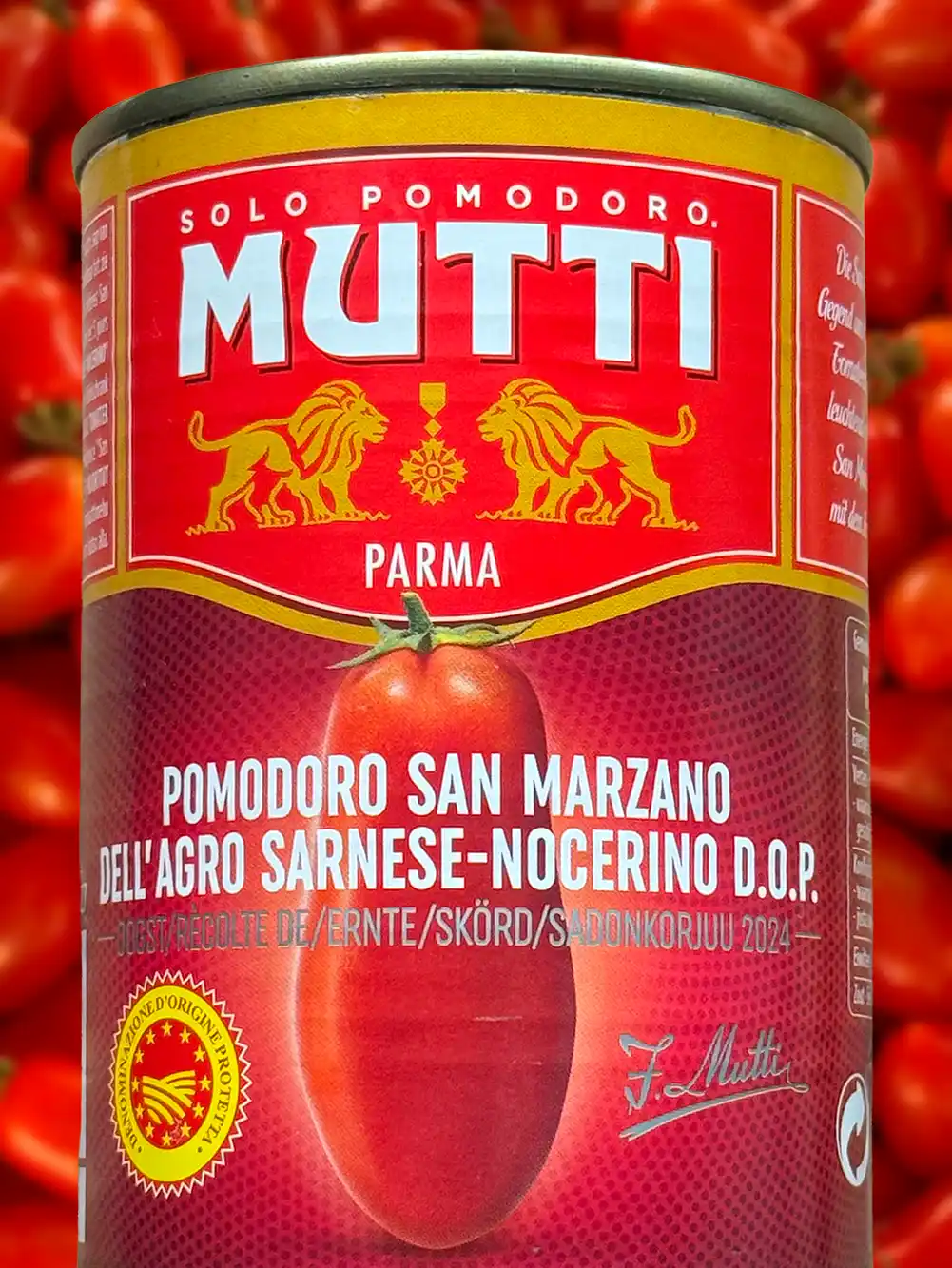 Eine Dose Mutti San Marzano-Tomaten mit rotem Etikett und gelben Akzenten, im Hintergrund Tomaten.