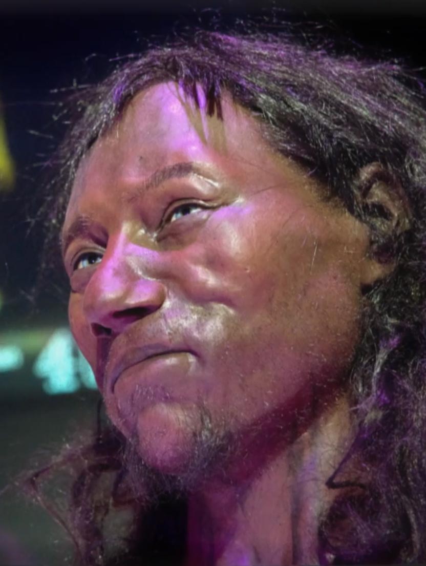 Cheddar-Man Nahaufnahme einer realistischen Museumsrekonstruktion eines antiken Menschen mit langen Haaren und ausdrucksstarken Gesichtszügen.
