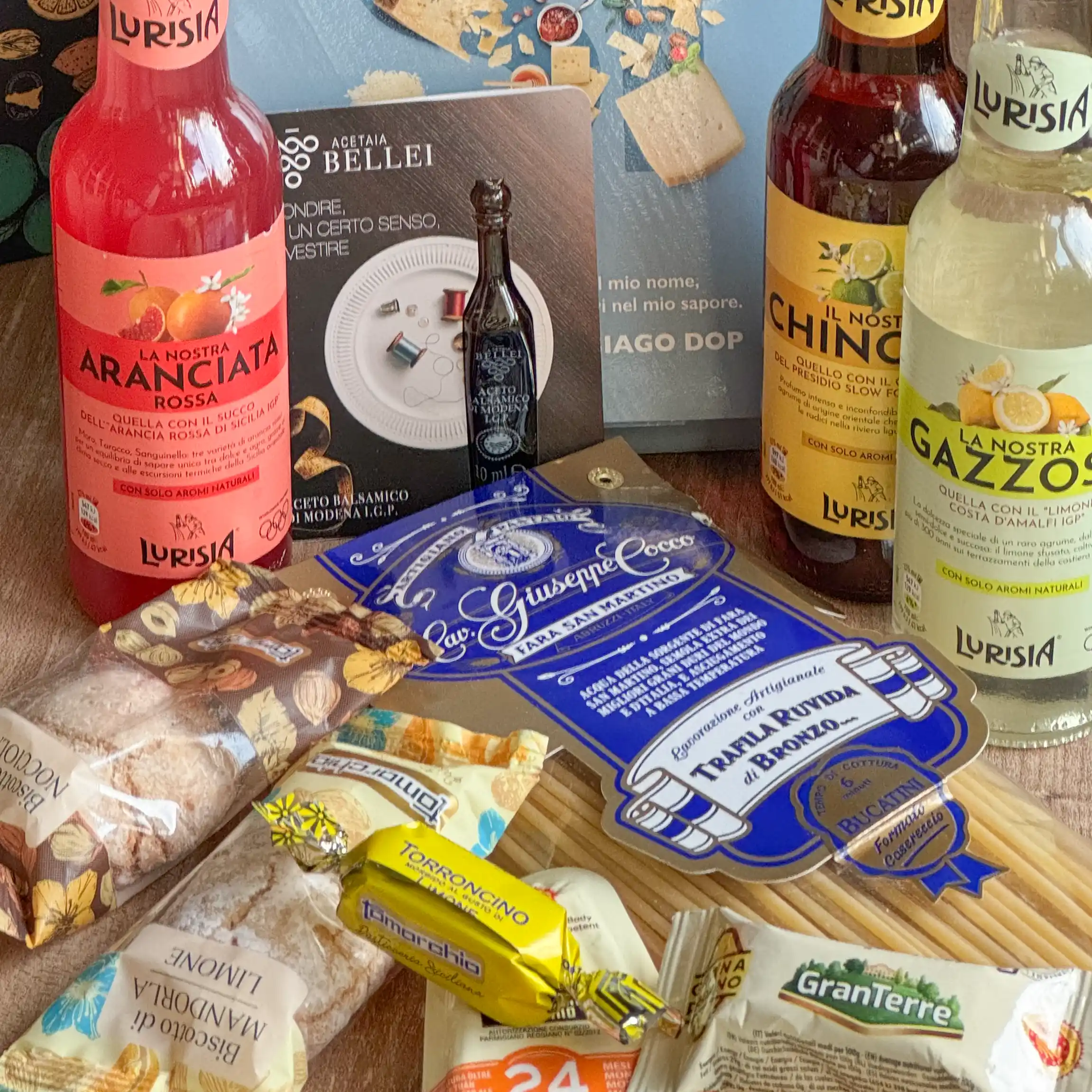 Verschiedene italienische Snacks, Getränke und Süßigkeiten, die zusammen auf einer Holzfläche ausgestellt sind.