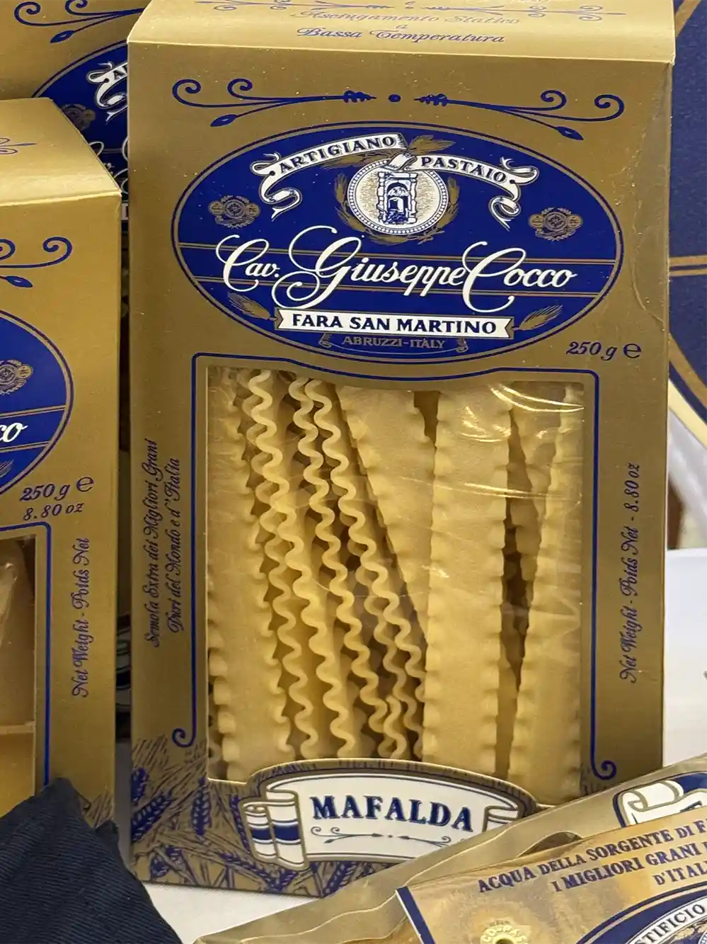 Eine Schachtel mit Cav. Giuseppe Cocco Mafalda mit goldenem und blauem Etikett, auf dem wellenförmige Nudeln abgebildet sind.