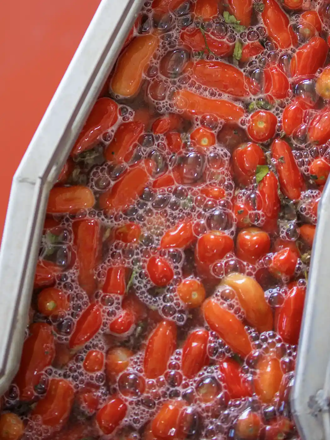 Rote Tomaten werden in einem mit Wasser und Seifenblasen gefüllten Behälter gewaschen.
