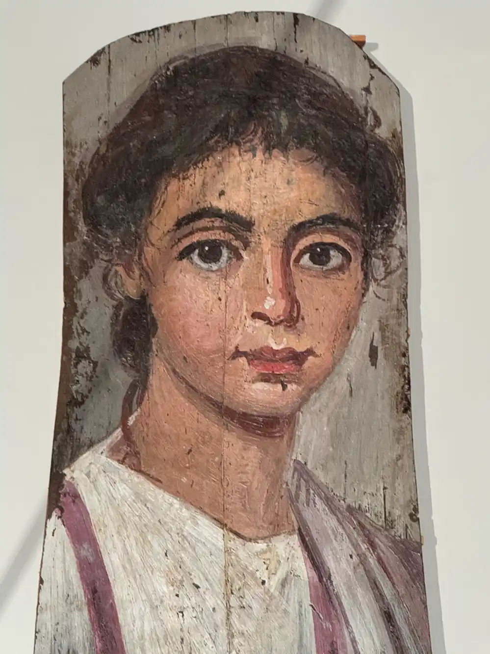 Antikes, auf einer Holztafel gemaltes Frauenporträt mit großen, ausdrucksstarken Augen und lockigem, dunklem Haar.