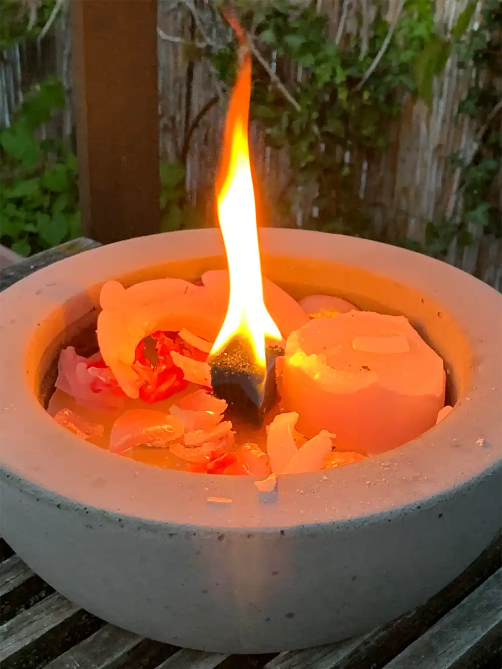 Feuer-Balkon-Wachsreste Eine große Kerze mit einer hellen Flamme brennt in einem runden Steinhalter, innen Wachsbrocken