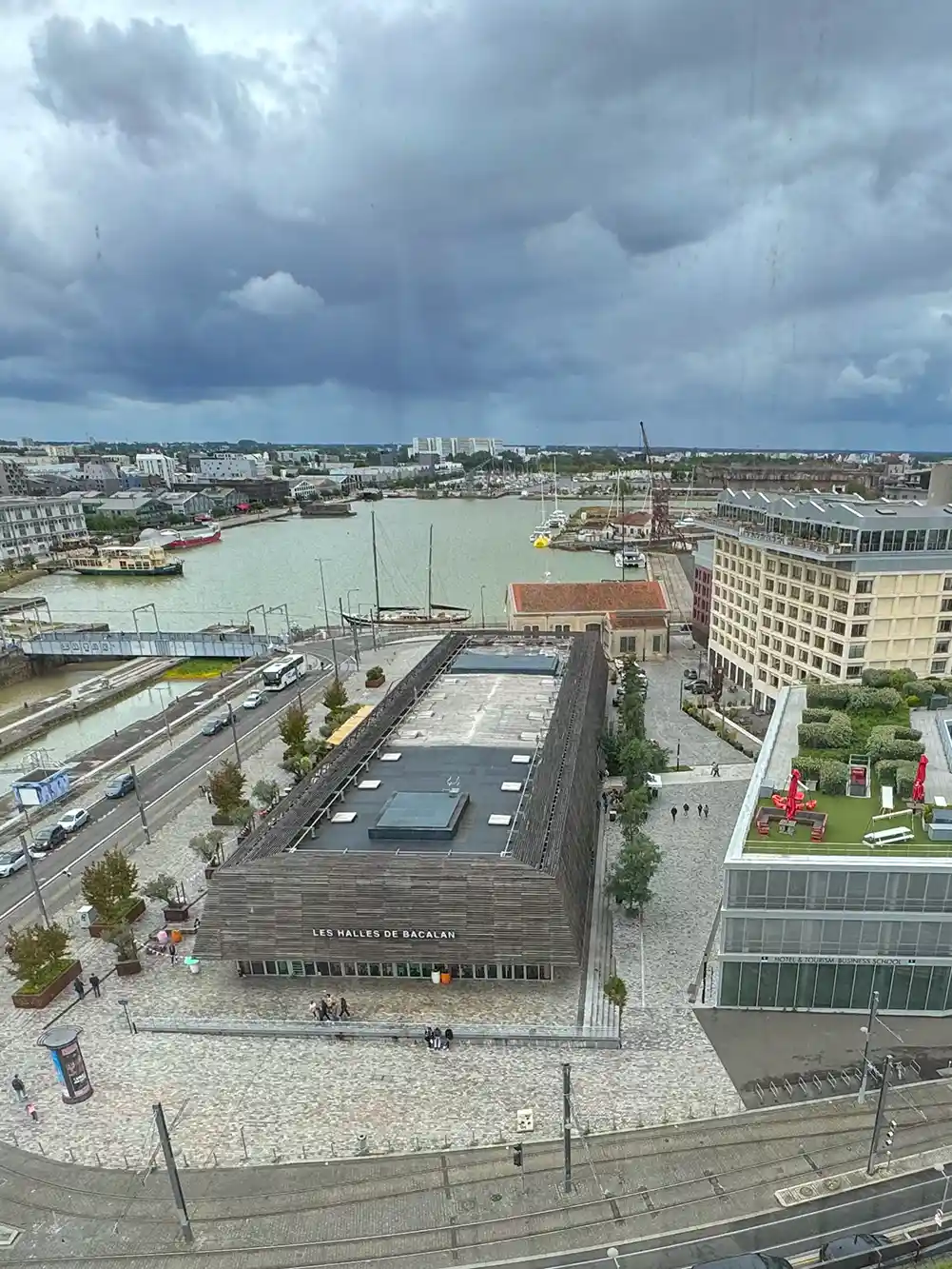Luftaufnahme einer Stadtlandschaft am Flussufer mit modernen Gebäuden unter einem bewölkten Himmel.