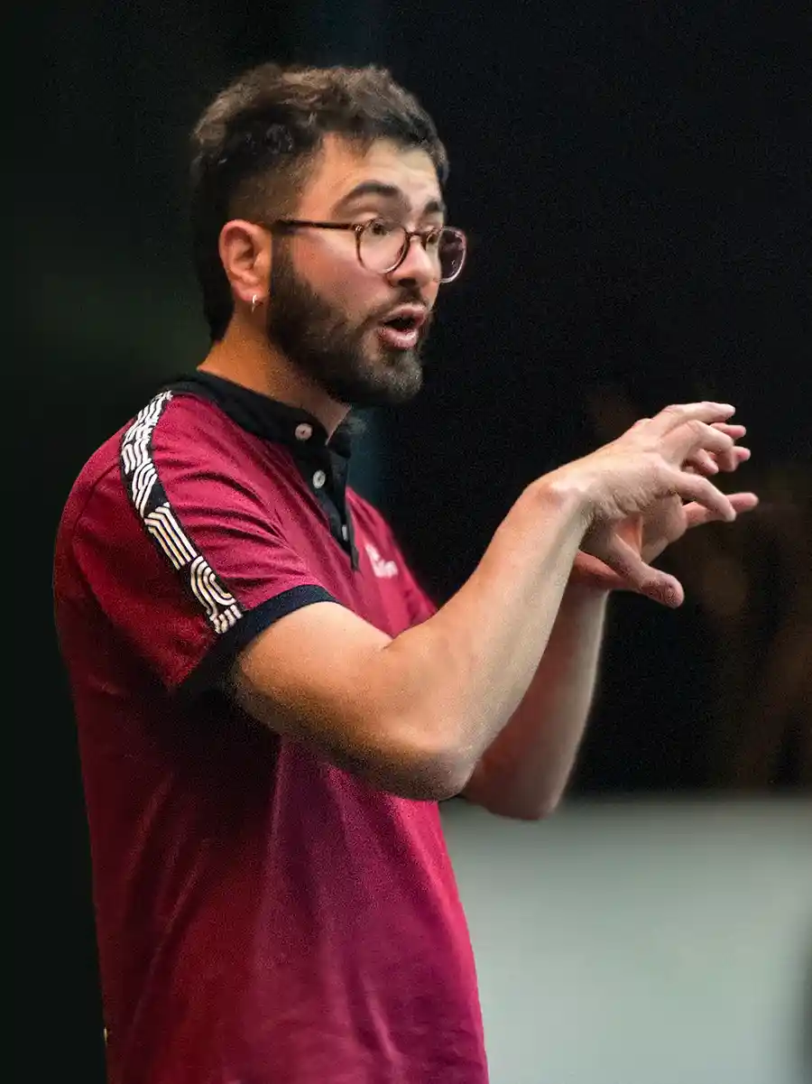Bordeaux-Geheimtipps-Via-Sensoria-Maxime Ein Mann in einem roten Polohemd gestikuliert, während er spricht, mit konzentrierter Miene und Brille.