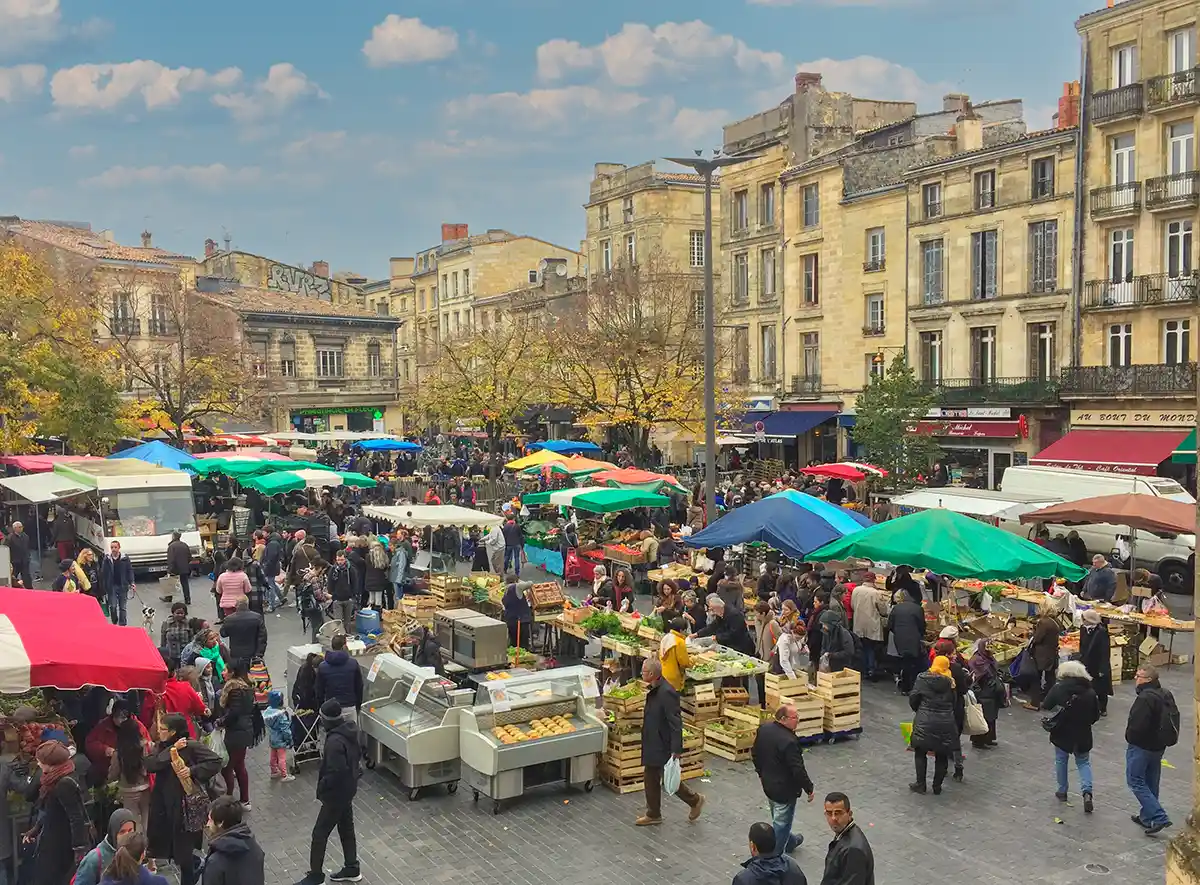 Belebter Markt im Freien mit bunten Schirmen, Essensständen und Menschenmassen auf einem europäischen Stadtplatz.