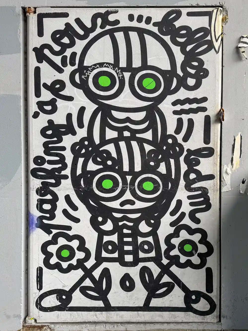 Schwarz-weiße Streetart von zwei Cartoonfiguren mit grünen Augen, Blumen und verspieltem Text auf einer Metalltür.