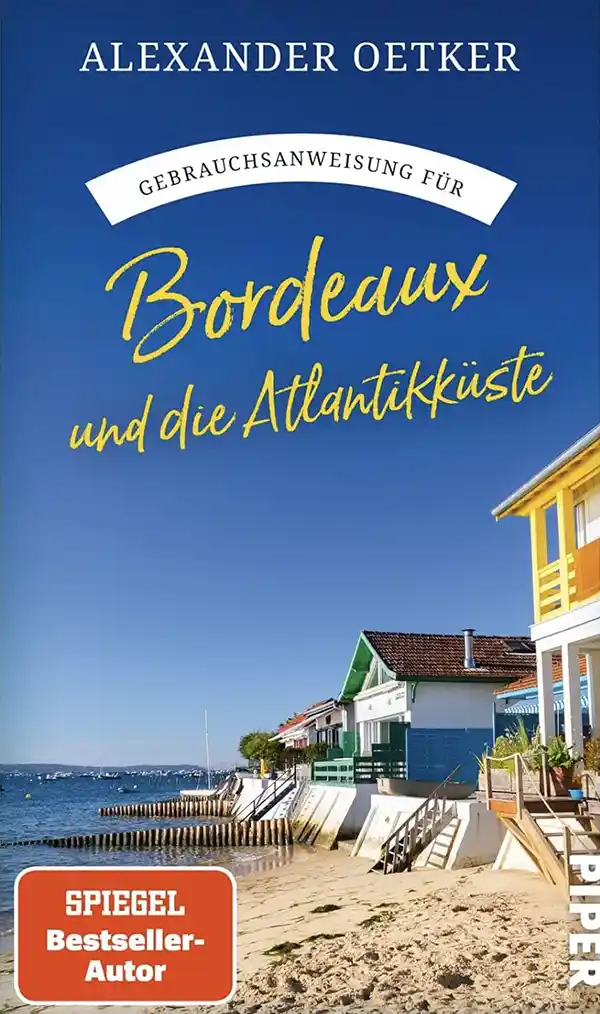Gebrauchsanweisung-Bordeaux-Cover Buchdeckel: Bunte Häuser an einem sonnigen Strand mit blauem Himmel, der Text lautet "Bordeaux und die Atlantikküste.".