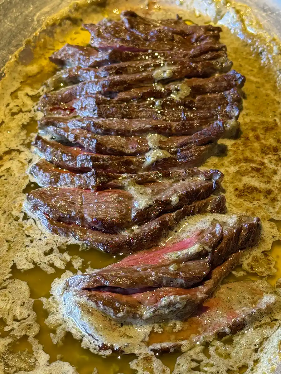 Geheimtipps-Bordeaux-L-Entrecote-Steak In Scheiben geschnittenes, medium-rare Steak in geschmolzener Butter und Saft auf einem silbernen Tablett