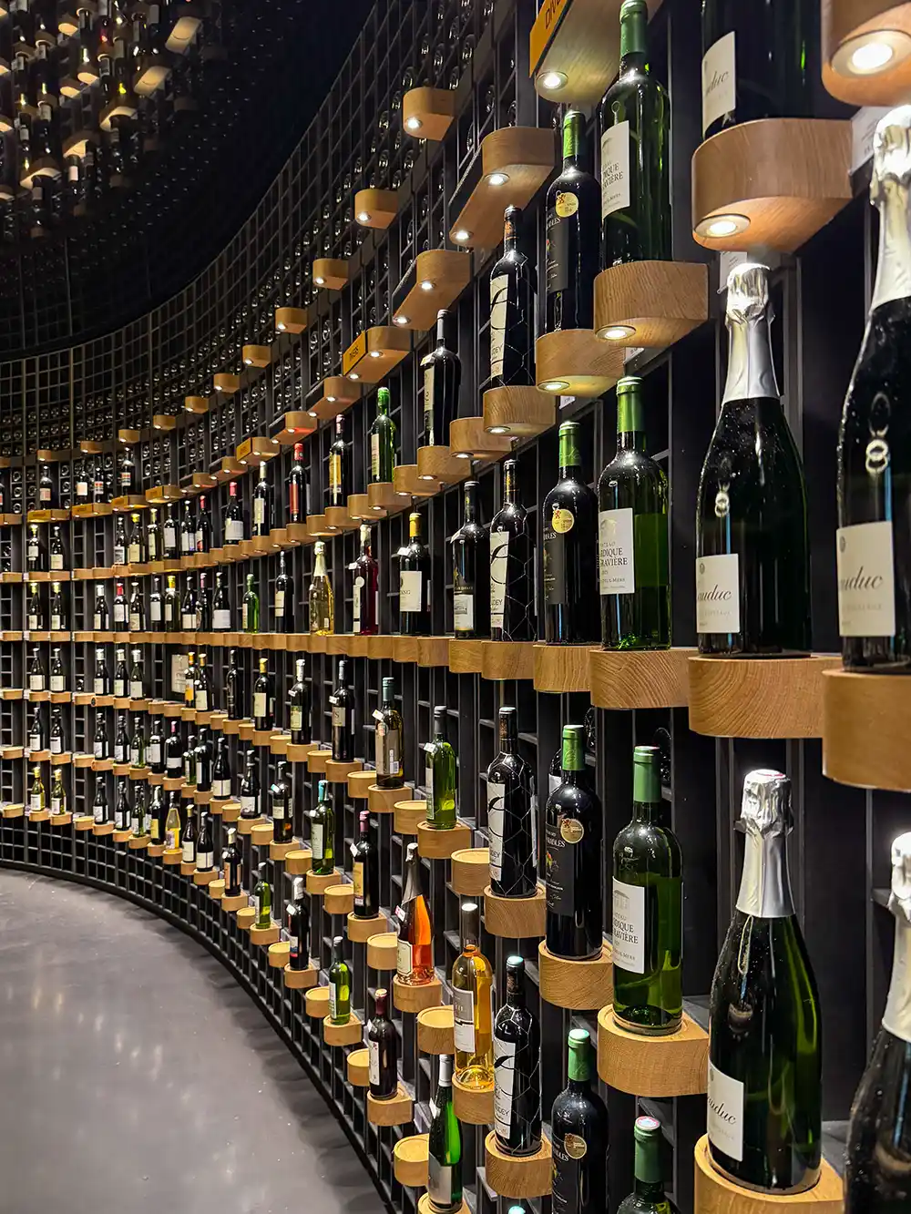 Eine geschwungene Wand mit Regalen mit verschiedenen Wein- und Champagnerflaschen