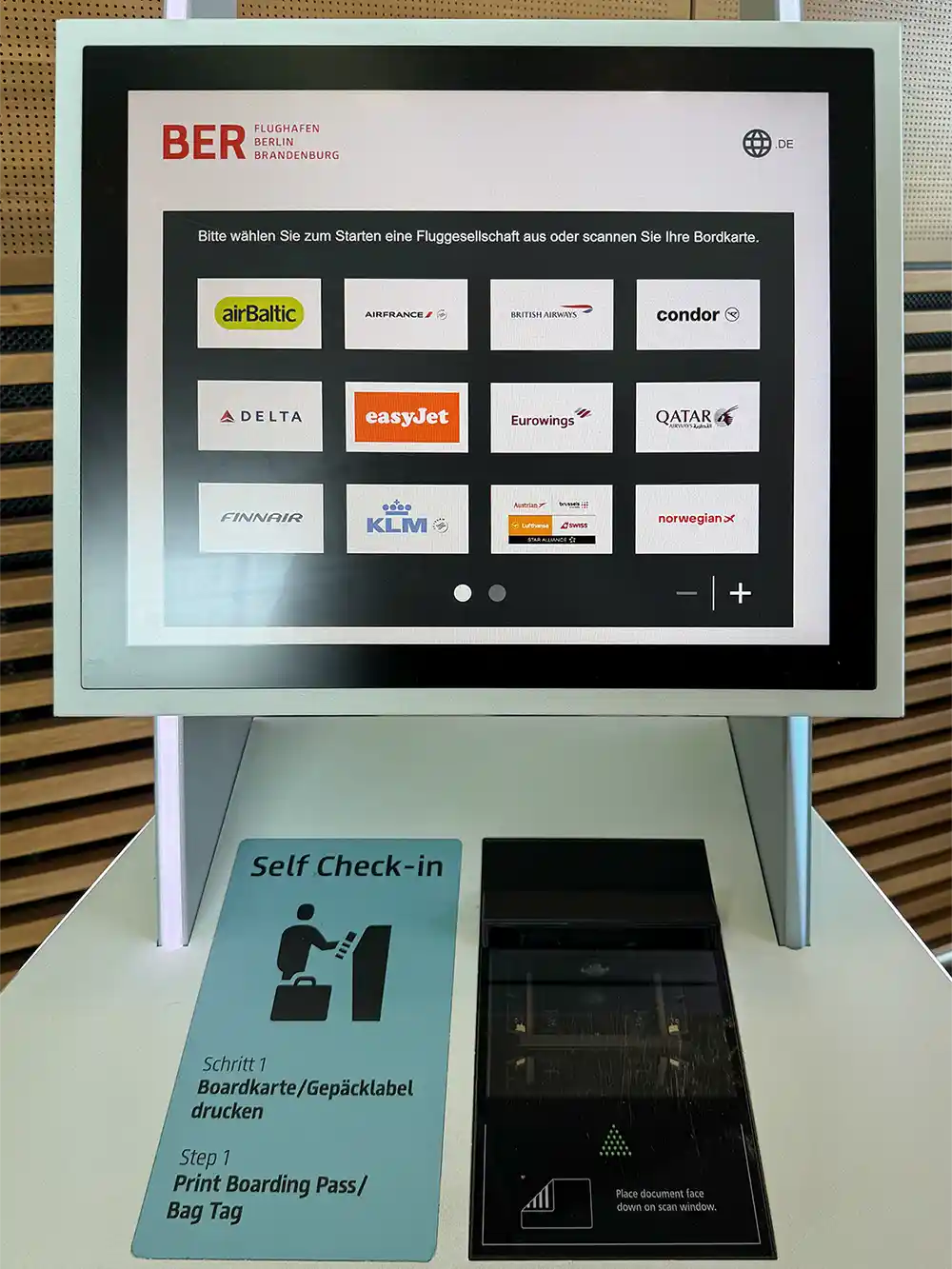 Der Bildschirm eines Selbstbedienungs-Check-in-Automaten am Flughafen Berlin-Brandenburg, auf dem die Fluggesellschaften auf Deutsch angezeigt werden.