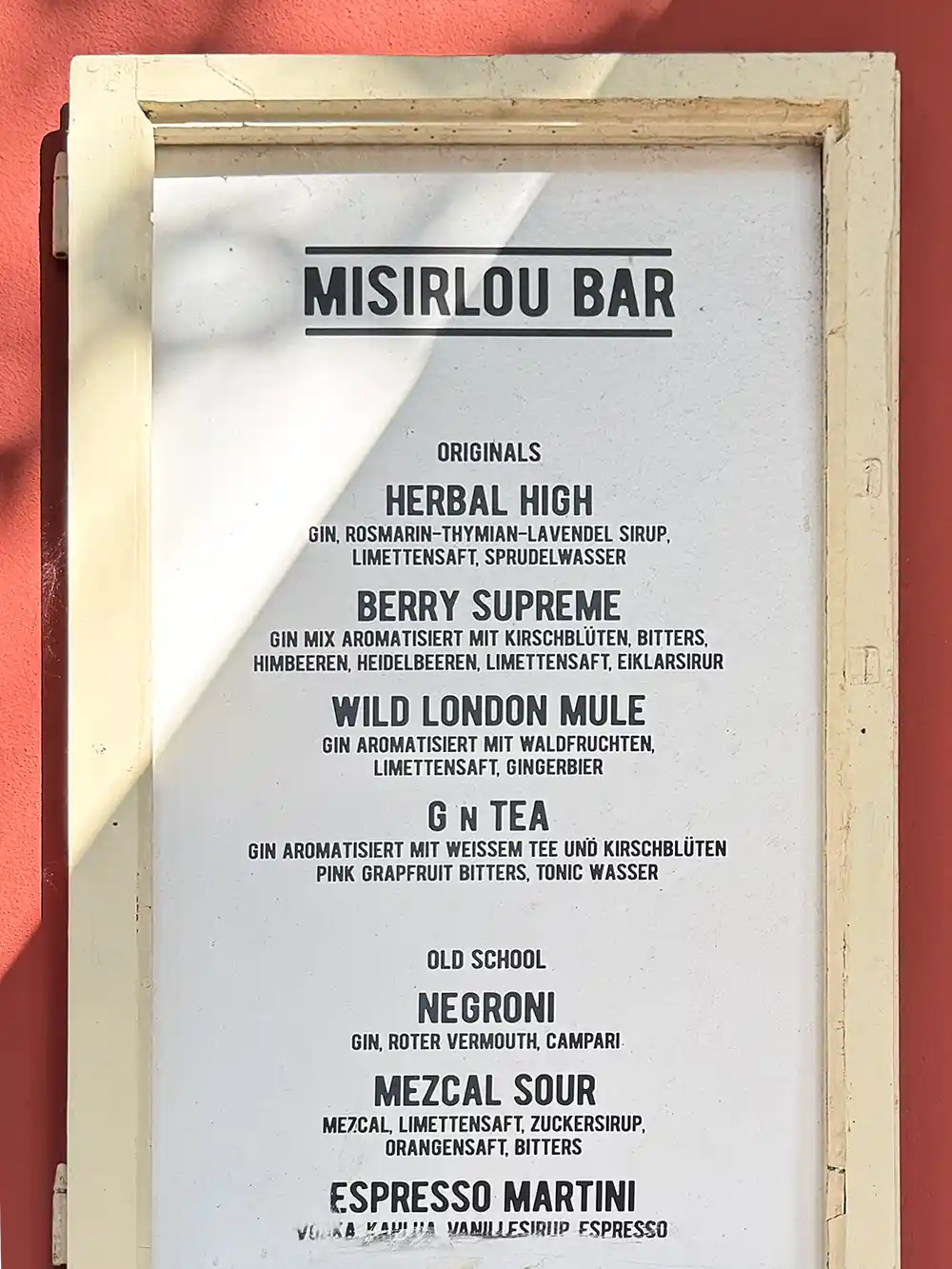 Menütafel für die Misirlou Bar mit einer Auflistung der Cocktails und ihrer Zutaten auf weißem Hintergrund.