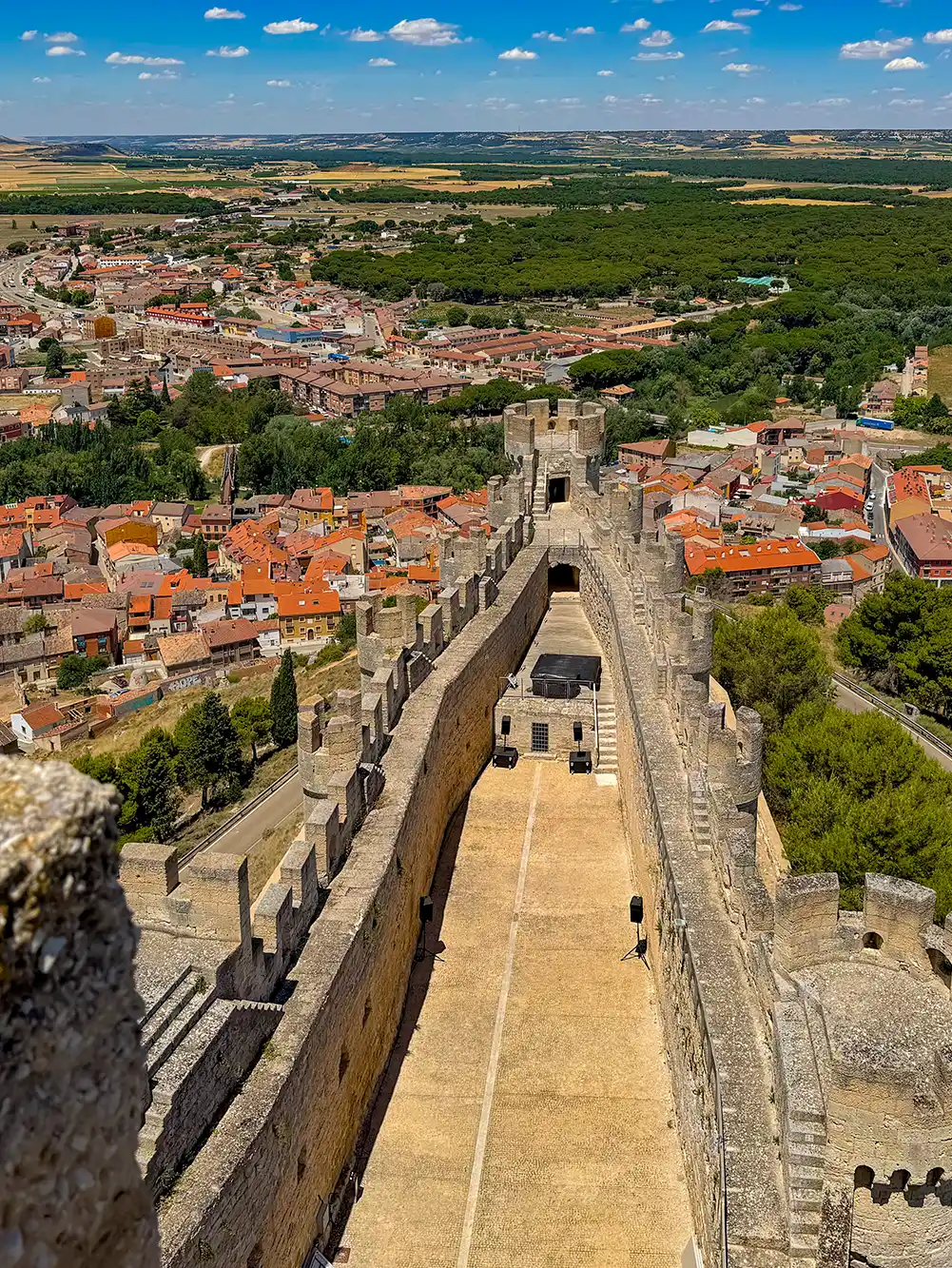 Penafiel-Burg Luftaufnahme einer Burgmauer aus Stein mit einer Stadt, Bäumen und Feldern im Hintergrund unter blauem Himmel.