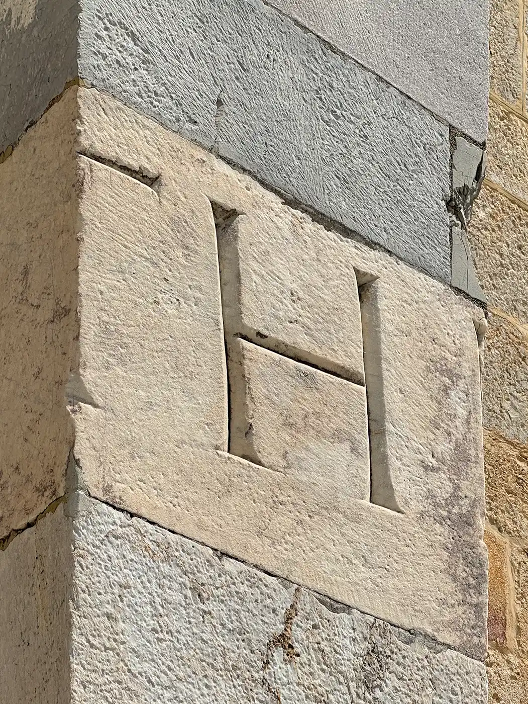 Ein großer Steinblock, in dessen Oberfläche der Buchstabe H eingraviert ist.