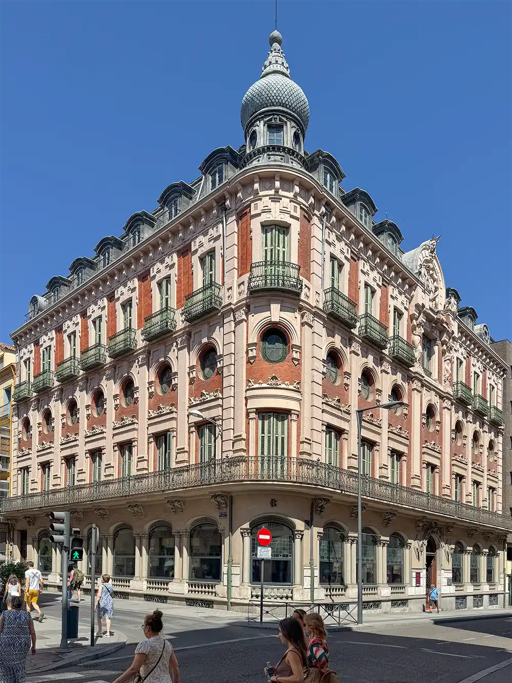 Valladolid-Circulo-de-recreo Historisches Eckgebäude mit verzierten Balkonen, Kuppeldach und Menschen, die davor spazieren gehen und Rad fahren.