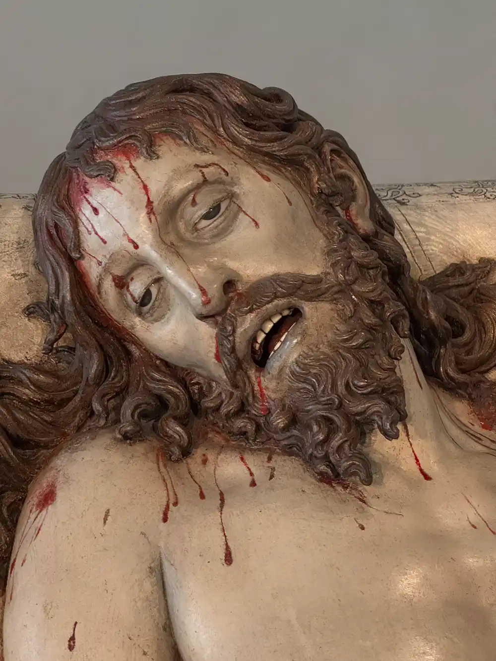Valladolid-Colegio-San-Gregorio-Skulptur-Jesus Eine Nahaufnahme einer Skulptur, die einen bärtigen Mann mit Wunden und Blut im Gesicht und am Kopf darstellt.