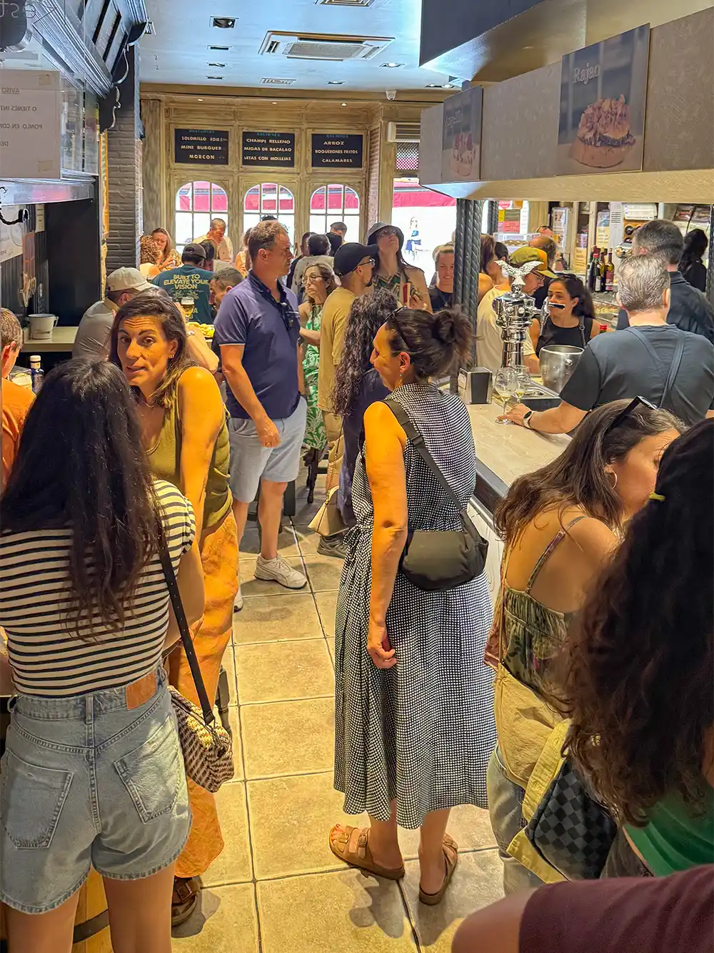 Valladolid-Restaurante-Jero Ein volles Café, in dem an einem sonnigen Tag Menschen in der Schlange stehen, sich unterhalten und an der Theke Essen bestellen.