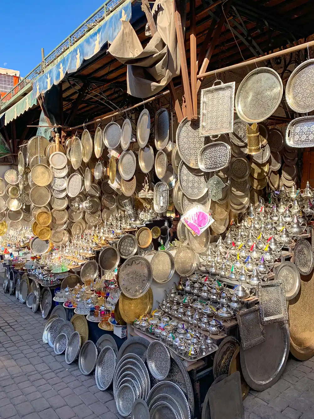 Basar-Messingteller An einem Marktstand ausgestellte Metallschalen und -teller, die unter blauem Himmel das Sonnenlicht reflektieren.