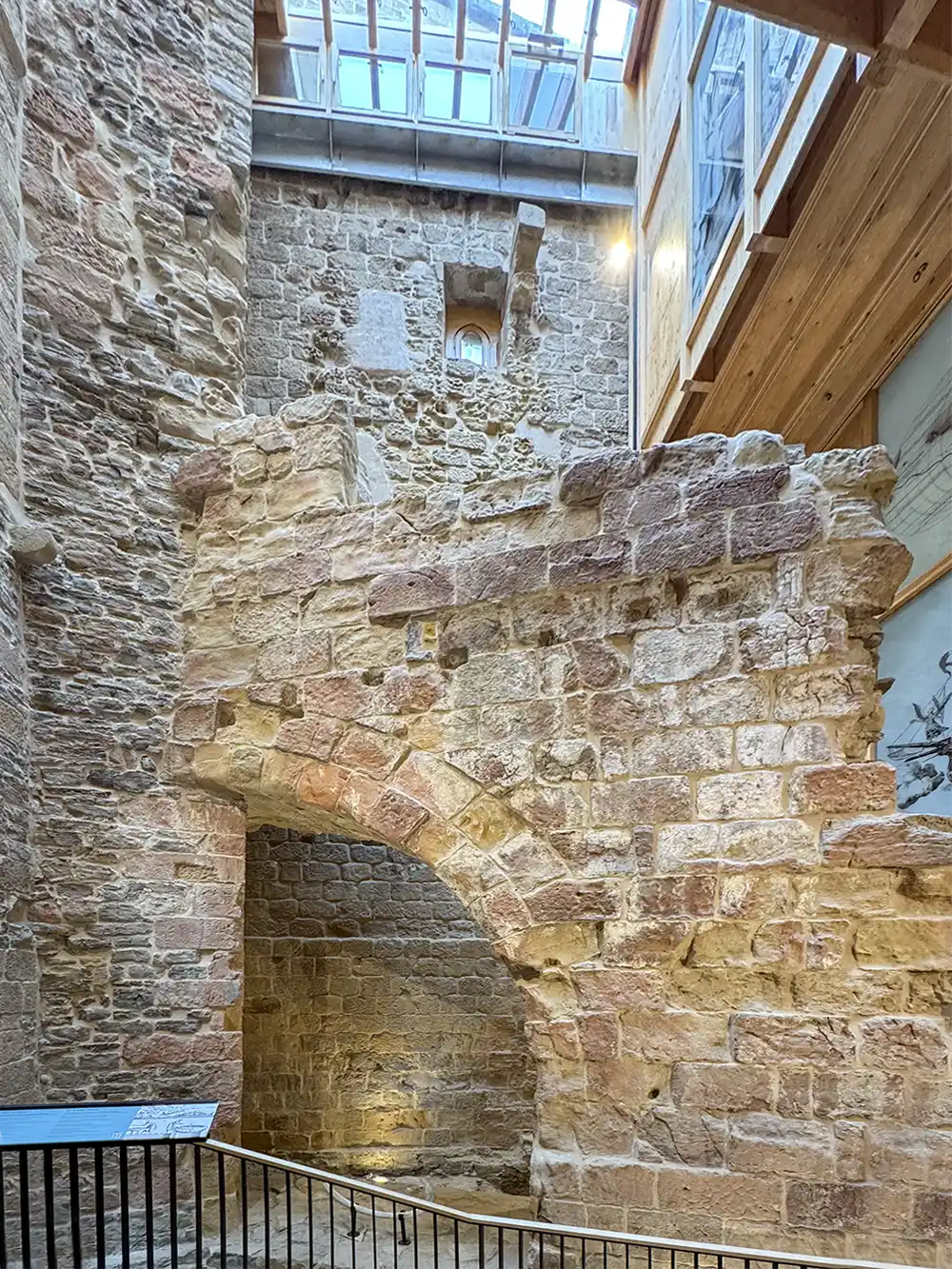 Getaria-Altstadt-Stuetzmauern-Tourismusbuero-3 Ein alter Steinbogen im Innenbereich mit unverputzten Ziegelwänden, Holzbalken und einem Oberlicht darüber.