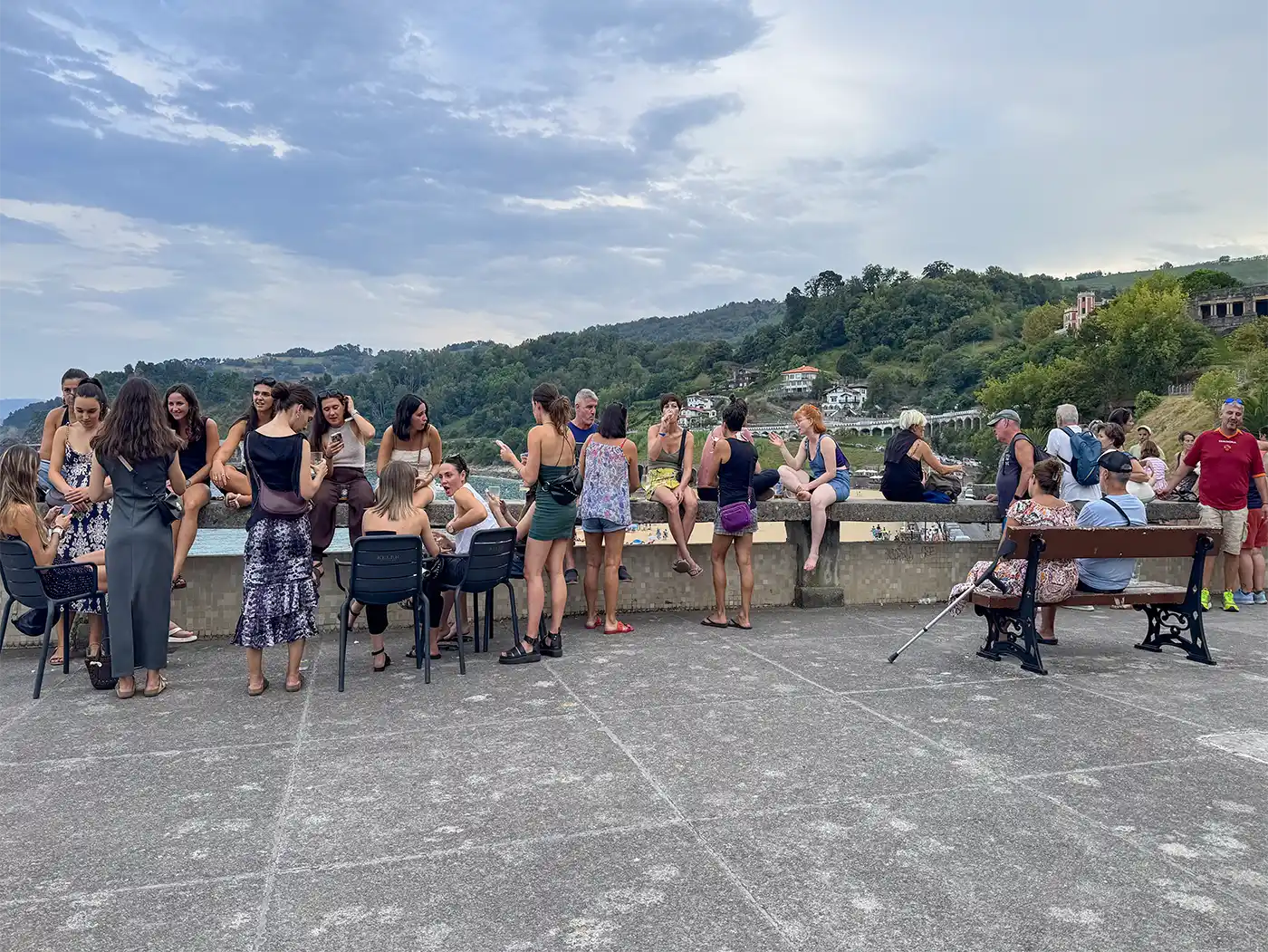 Getaria-Dorf-Terrasse-2 An einem bewölkten Tag versammelt sich eine Gruppe von Menschen im Freien in der Nähe des Ufers und unterhält sich.