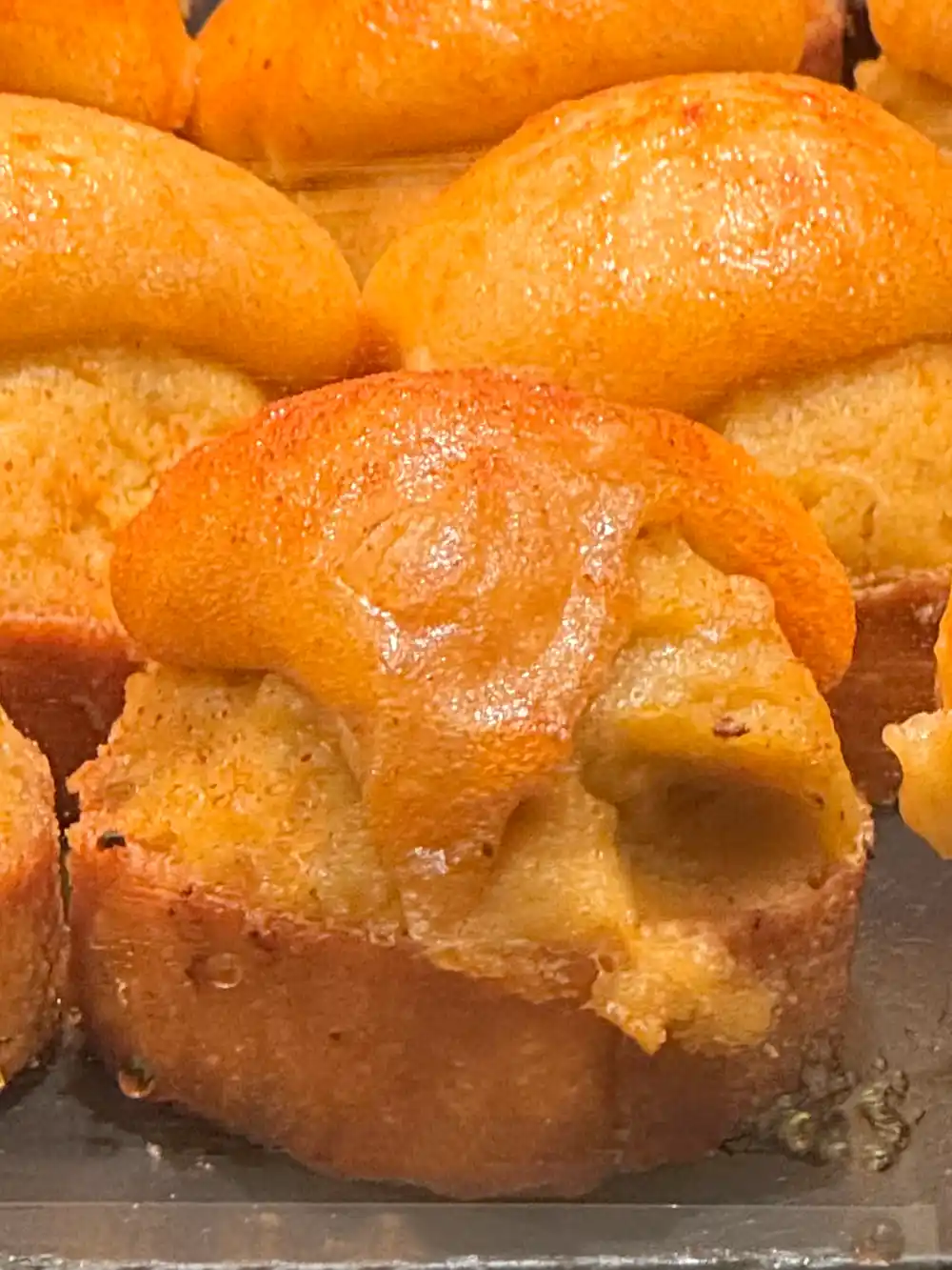Nahaufnahme von goldbraunen überackenen Pintxos mit gewölbten Oberseiten, die dicht nebeneinander auf einem Blech angeordnet sind.