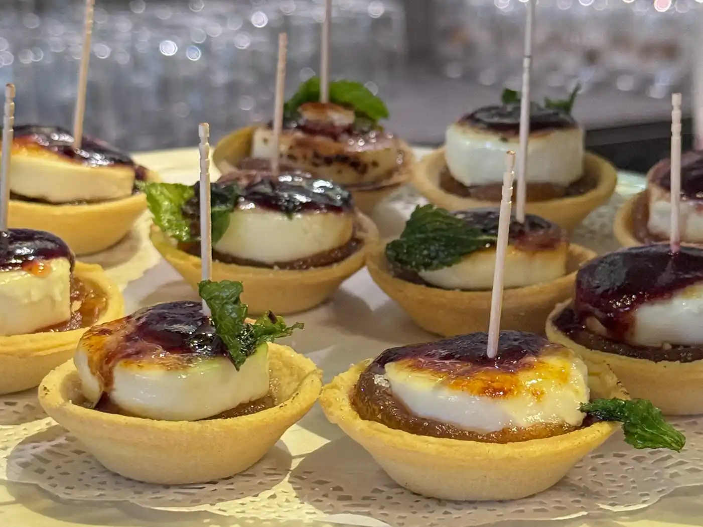 Gebäck-Törtchen mit Käse, Fruchtkonfitüre und einem Minzblatt, die in den Pintxo-Bars als klassischer Snack serviert werden.