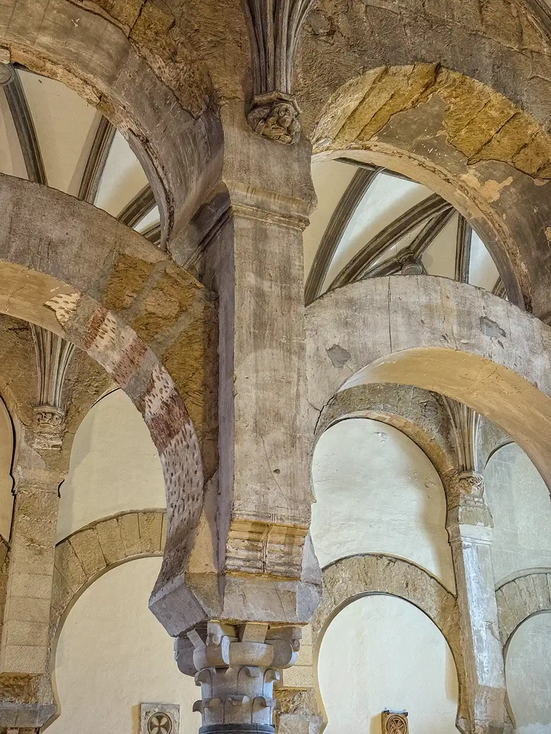 Cordoba-Mezquita-gotisch-maurische-Boegen-Neidkoepfe Gotische Steinbögen und maurische Säulen in einer alten Gewölbedecke.