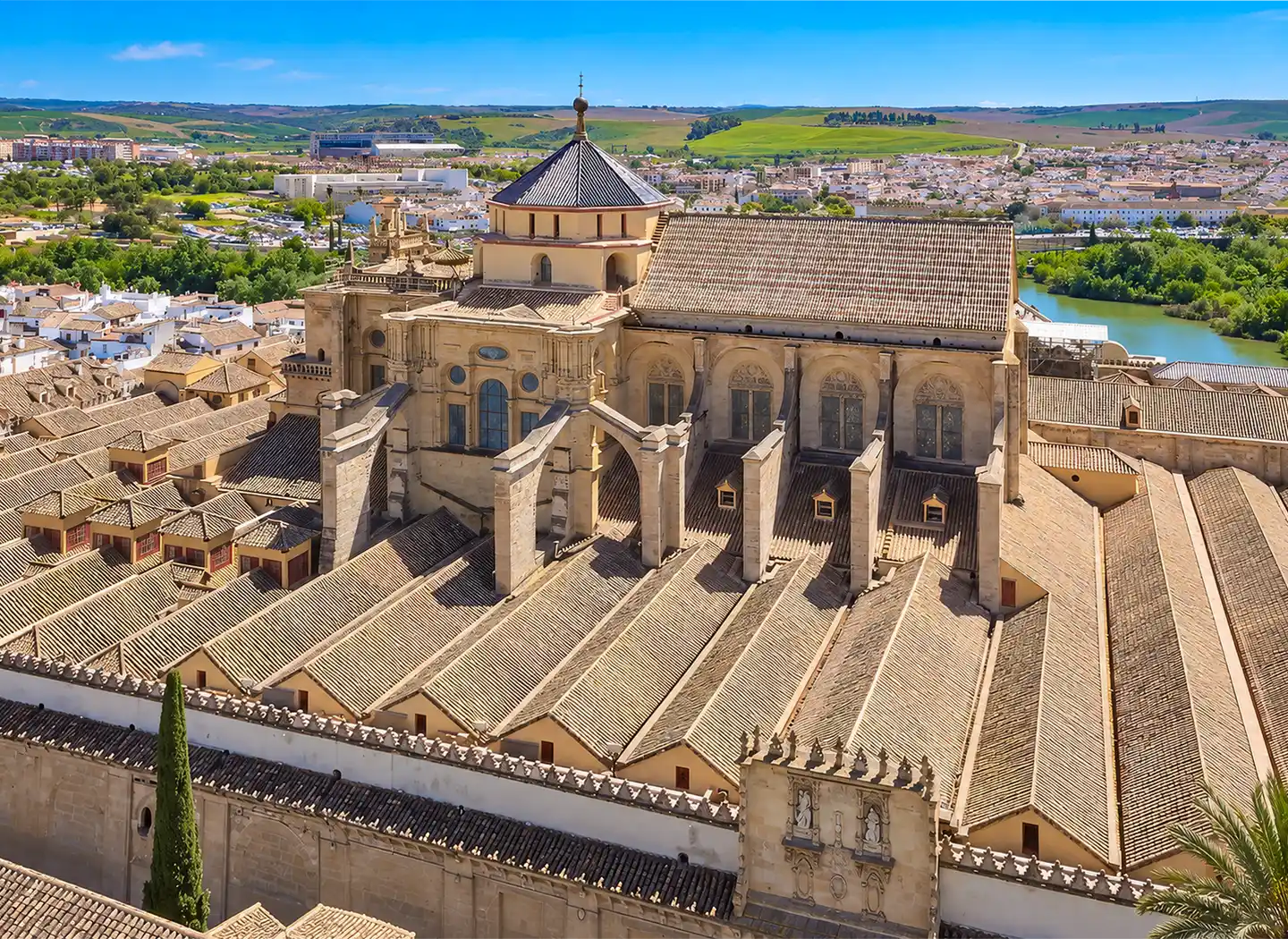 Luftaufnahme der Moschee-Kathedrale von Córdoba mit ihrem Ziegeldach und der zentralen Kuppel, mit Blick auf einen Fluss und die Stadt.