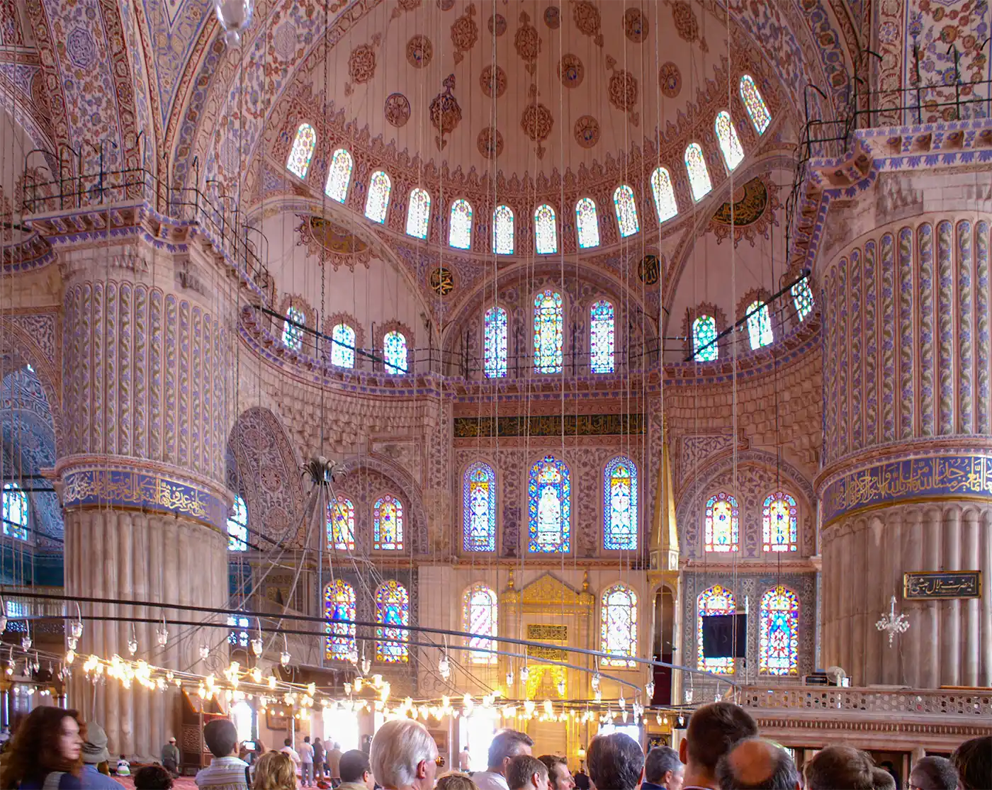 Istanbul-Blaue-Moschee-innen Das Innere der Blauen Moschee in Istanbul mit kunstvoll verzierten Kuppeln, großen Säulen und farbenprächtigen Buntglasfenstern.