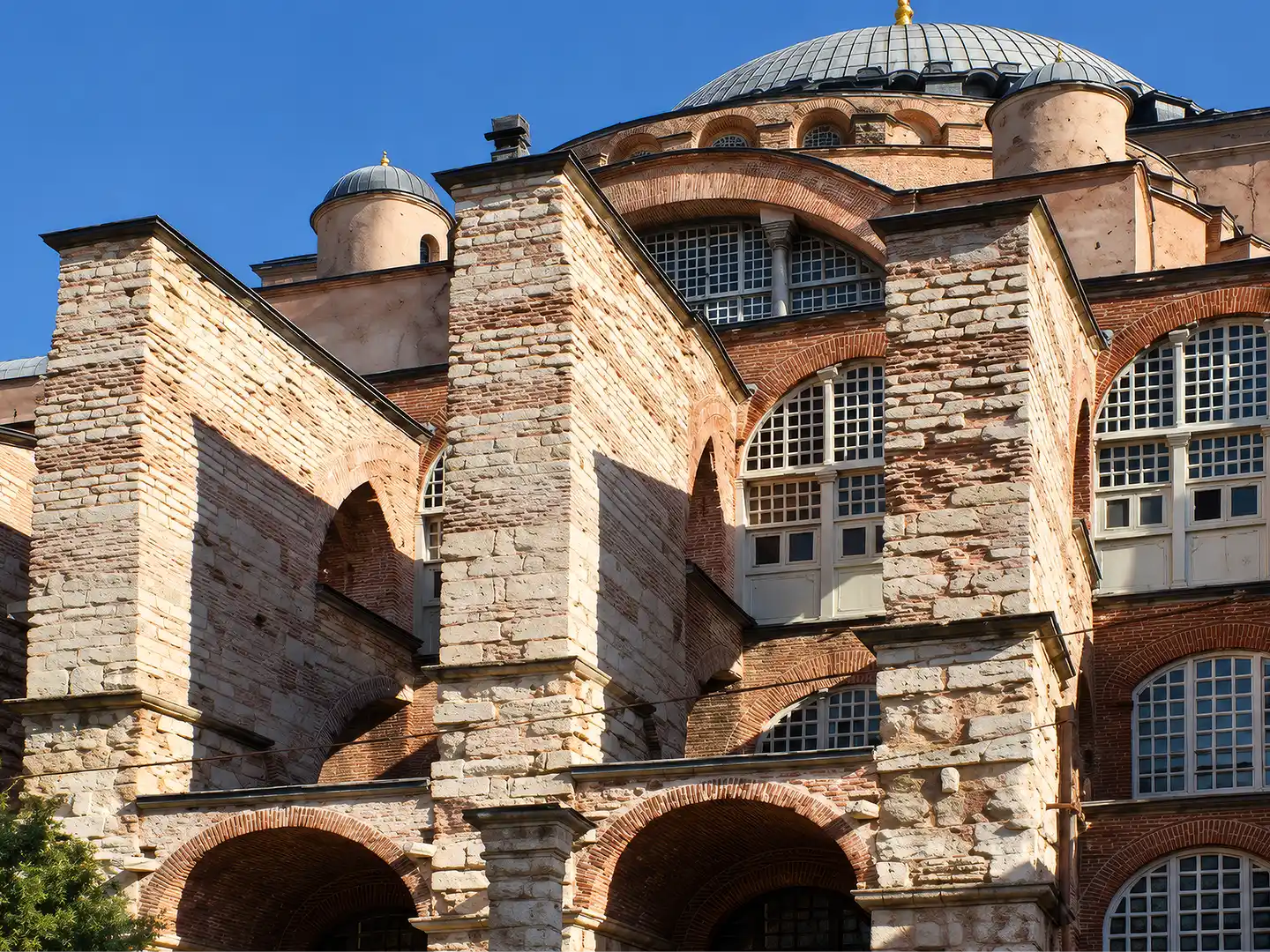 Istanbul-Hagia-Sophia-Stuetzmauern Außenansicht der Hagia Sophia, einer der wichtigsten Sehenswürdigkeiten Istanbuls, mit Ziegelmauerwerk, Bogenfenstern und einer zentralen Kuppel.