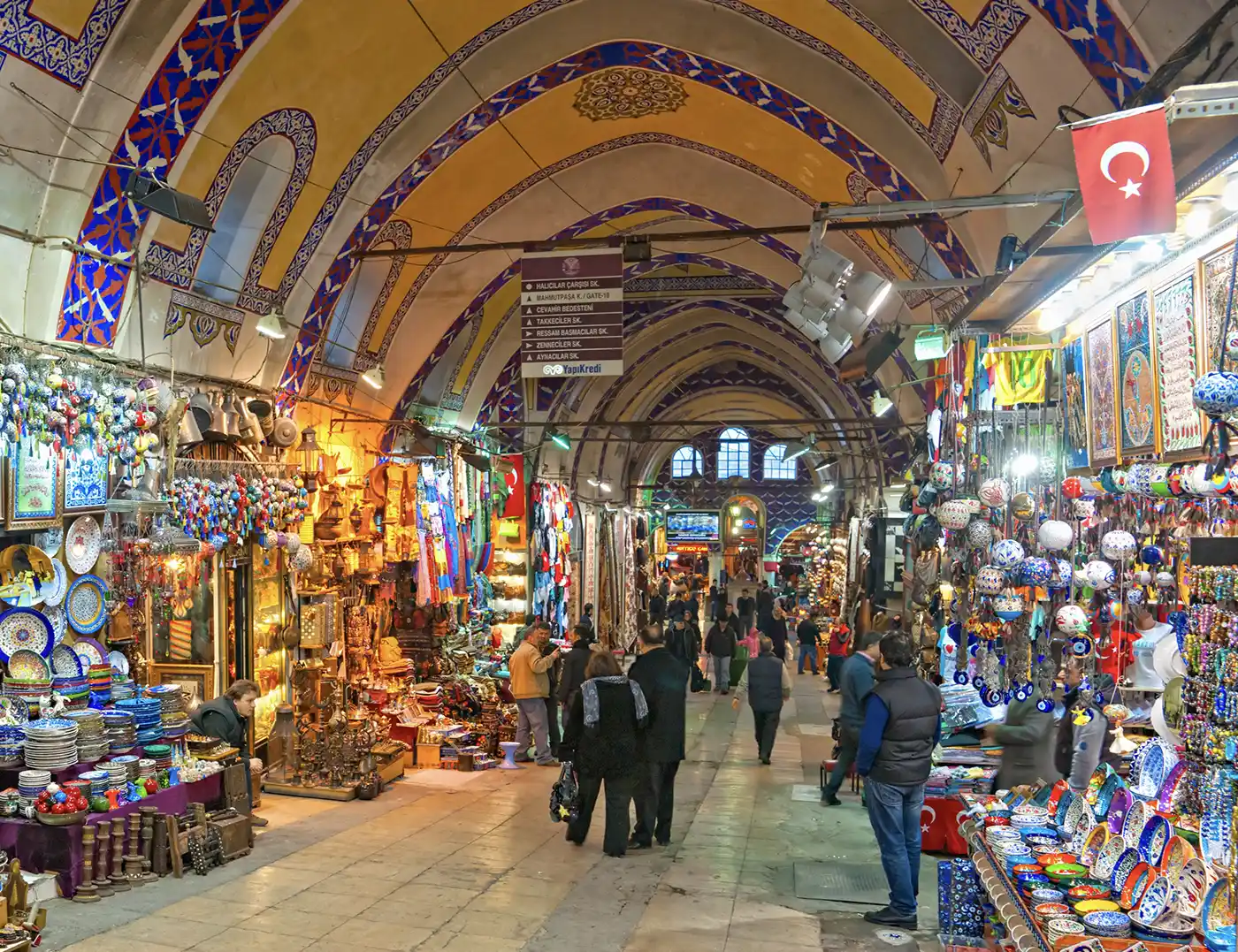 Istanbul-Sehenswuerdigkeiten-Grosser-Basar Ein Blick entlang eines belebten, gewölbten Ganges des Großen Basars in Istanbul, der von bunten Geschäften gesäumt ist.