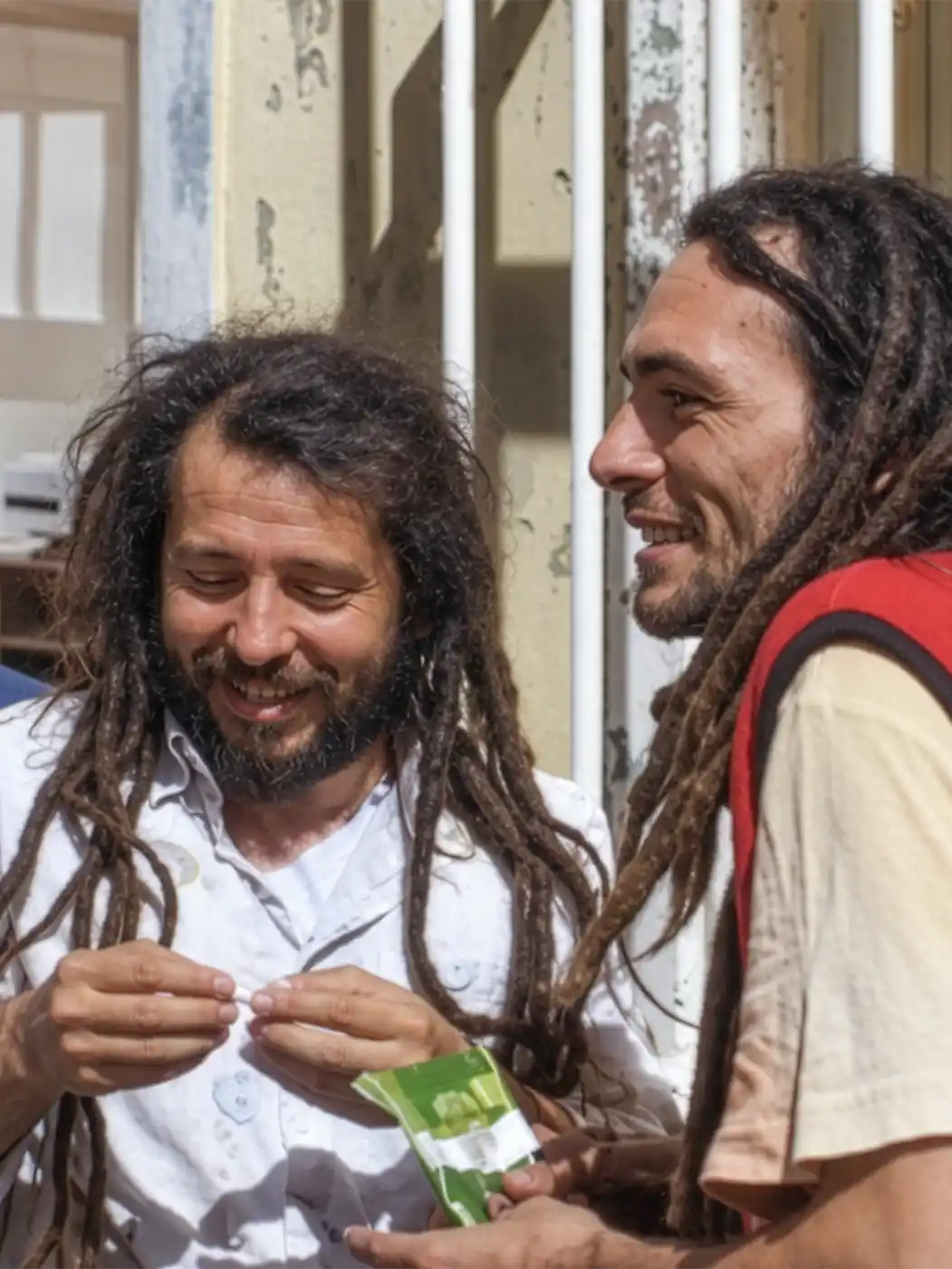 Istanbul-zwei-Maenner Zwei Männer mit Dreadlocks, die lächeln, während sie ein kleines Päckchen in der Hand halten.