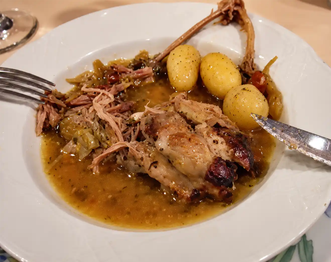 Geschmortes Fleisch mit ganzen Kartoffeln und Gemüse in einer flachen Schüssel.